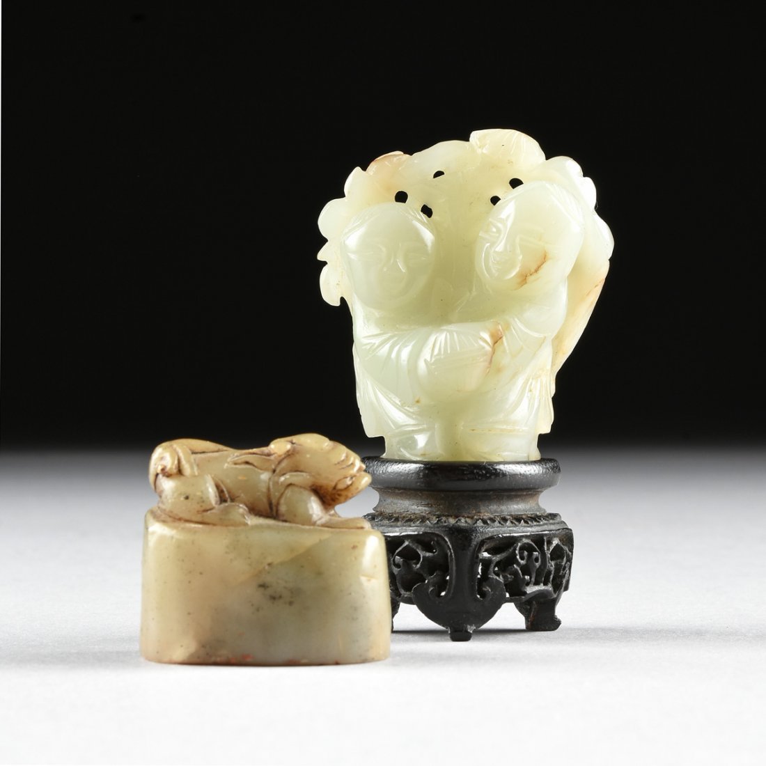 A GROUP OF TWO CHINESE SMALL JADE CARVINGS, 20TH: A GROUP OF TWO CHINESE SMALL JADE CARVINGS, 20TH CENTURY, the seal of shaped oval form and a dark celadon color with backside enclosing a "mutton fat" streak and modeled as a miniature recumbent Buddh