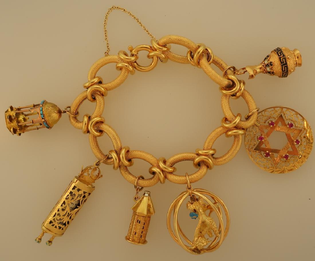 18 K Charm Bracelet w/ Six Large Charms 75.7 Grams: 18 KT Charm Bracelet w/ Six Large Charms, bracelet marked "750", 18 kt Greek Enameled Urn, Star of David w/ Turqoise, Tower of Lucerne, Mazzuza, 14 kt Poodle w/ Shoe in an Orb and a 14 kt Bird Cage wi