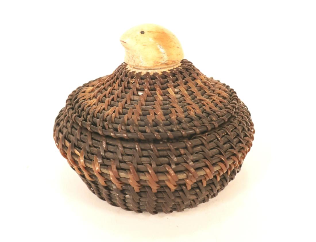 Joshua Sakeagak Baleen and Walrus Lidded Basket: An Inuit two tone baleen lidded basket by Joshua Sakeagak, (1920 - 1981 Barrow Alaska) with light and dark brown baleen in banding of the body and lid, a carved bone seal head on a small disk for the 