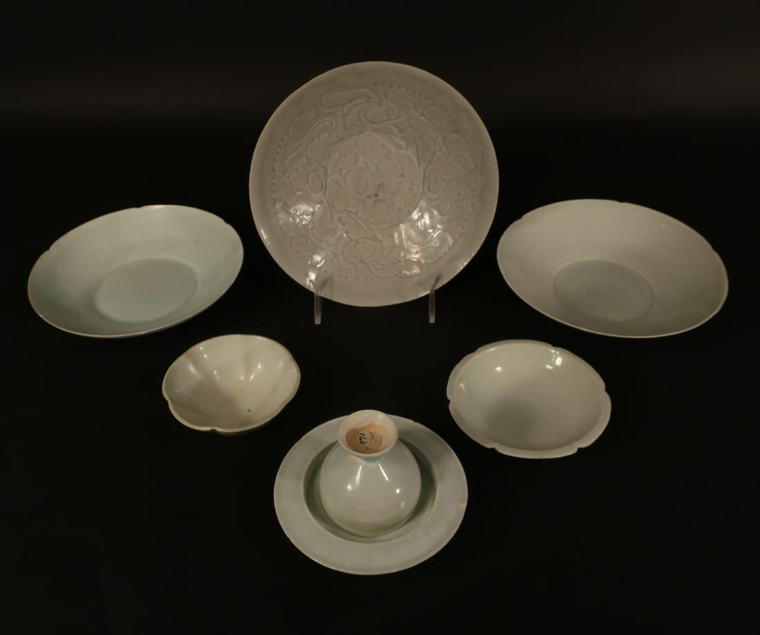 6 Chinese White/Celadon Dishes, Sang to Qing: Porcelain, some of Ching-pai coloration, Comprising: a wine cup and saucer, 5 bowls/dishes, the largest with raised leaf and cloud decoration, 2 middle size with underglaze leaf and fern design, large