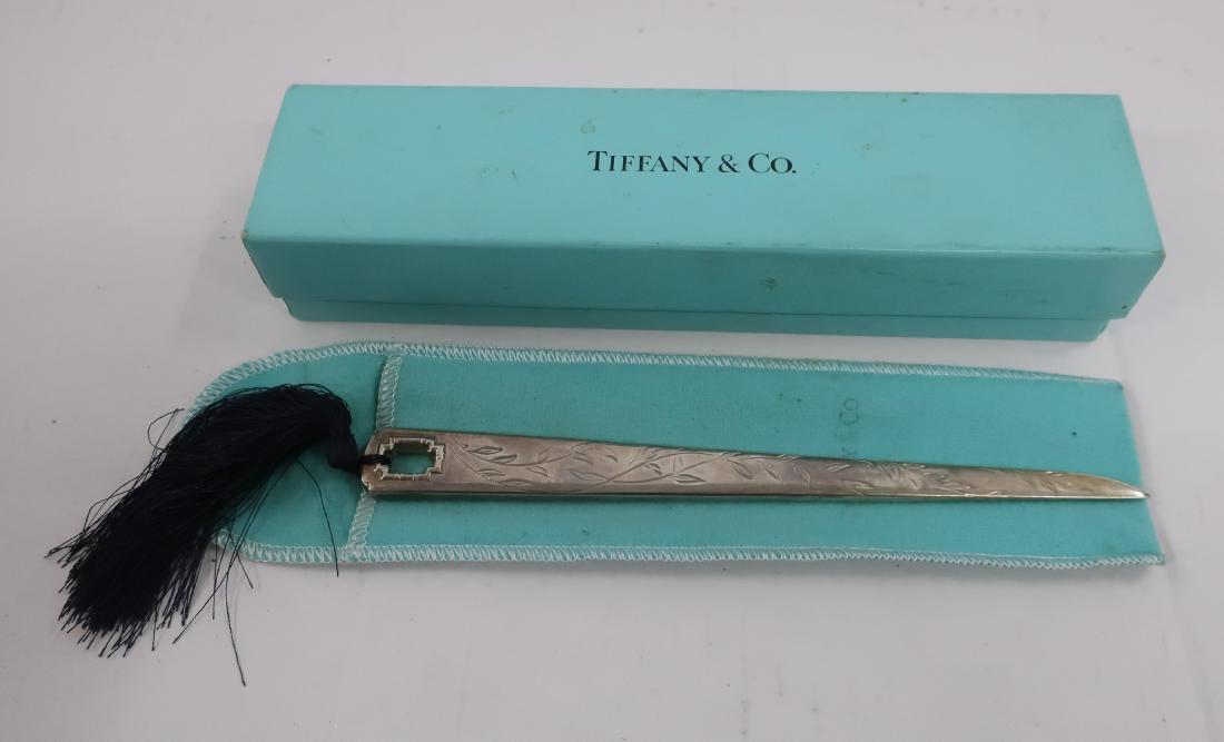 Tiffany Letter Opener: Bamboo design framed end opening. Leaves and vines on handle. Signed Tiffany 1999 .925. Dark blue tassel. In Tiffany cloth slipcase and box. DIMENSIONS: Blade 7.75" 11.5 overall w/ tassel We encourage