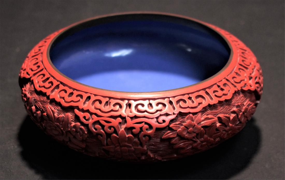 Chinese Red Cinnabar Bowl: Sharply carved with flowers in relief, bronze rim and foot, blue enamel interior and bottom 2 1/2" H x 6 1/4" Dia. Property from the collection of Arthur & Lillian Weiss, Little Deer Isle, Maine