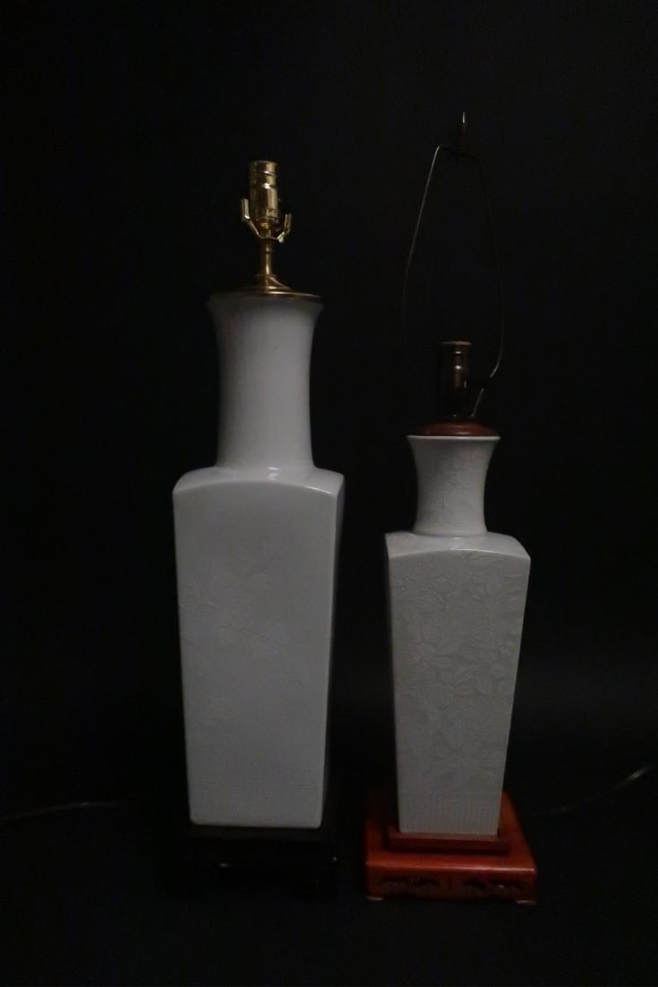 2 Asian Floral Painted White Porcelain Lamps: Two Asian White on White Porcelain Floral Painted Square Vase Form Vases on Carved Wooden Stands Vases 19 and 15"H, top of finial 27 and 29"H (DWYL8669/2)(MM)