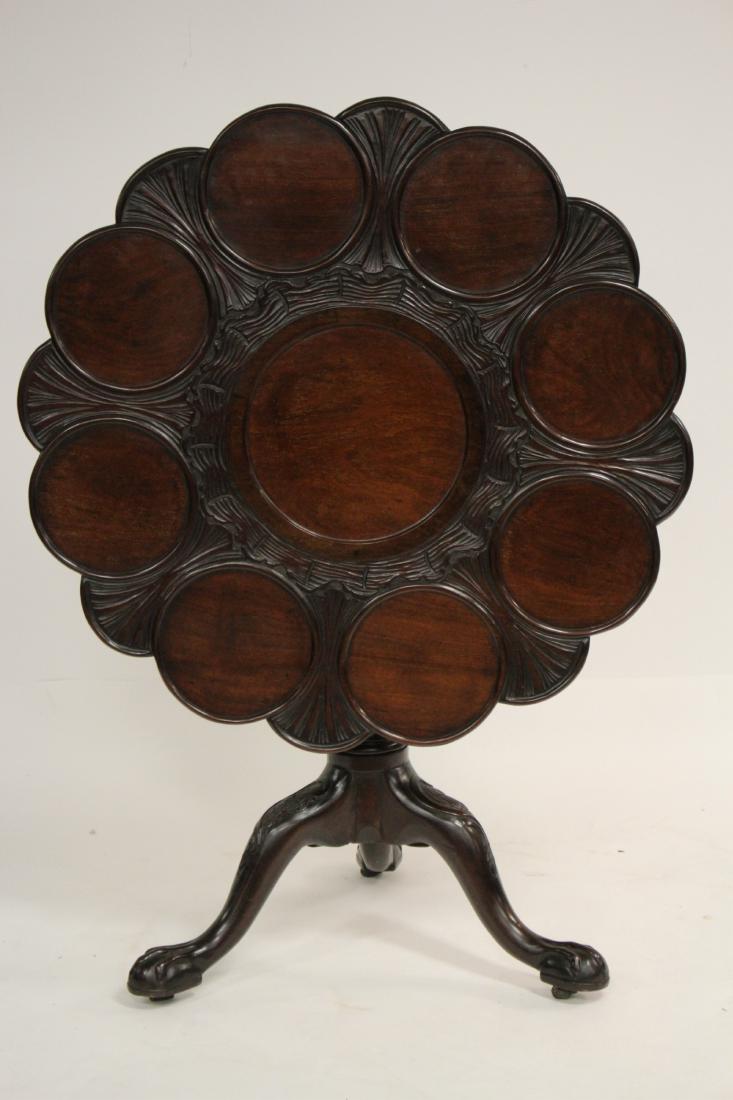 19th C. English Mahogany Carved Supper Table: English Mahogany Carved Tilt Top Supper Table, 19th C., with wavy carving along circular sinkings for plates, on birdcage base and fluted pedestal with tripod base, claw and oval egg shaped hoofed fee
