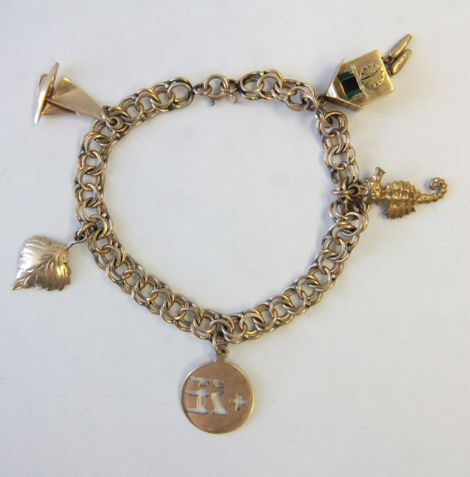 14K Yellow Gold Double Spiral Link Charm Bracelet: Five charm including seahorse, sailboat, etc. Gross weight of 16.3 grams. 7" long. Property from the estate of Rosalie Coe Weir