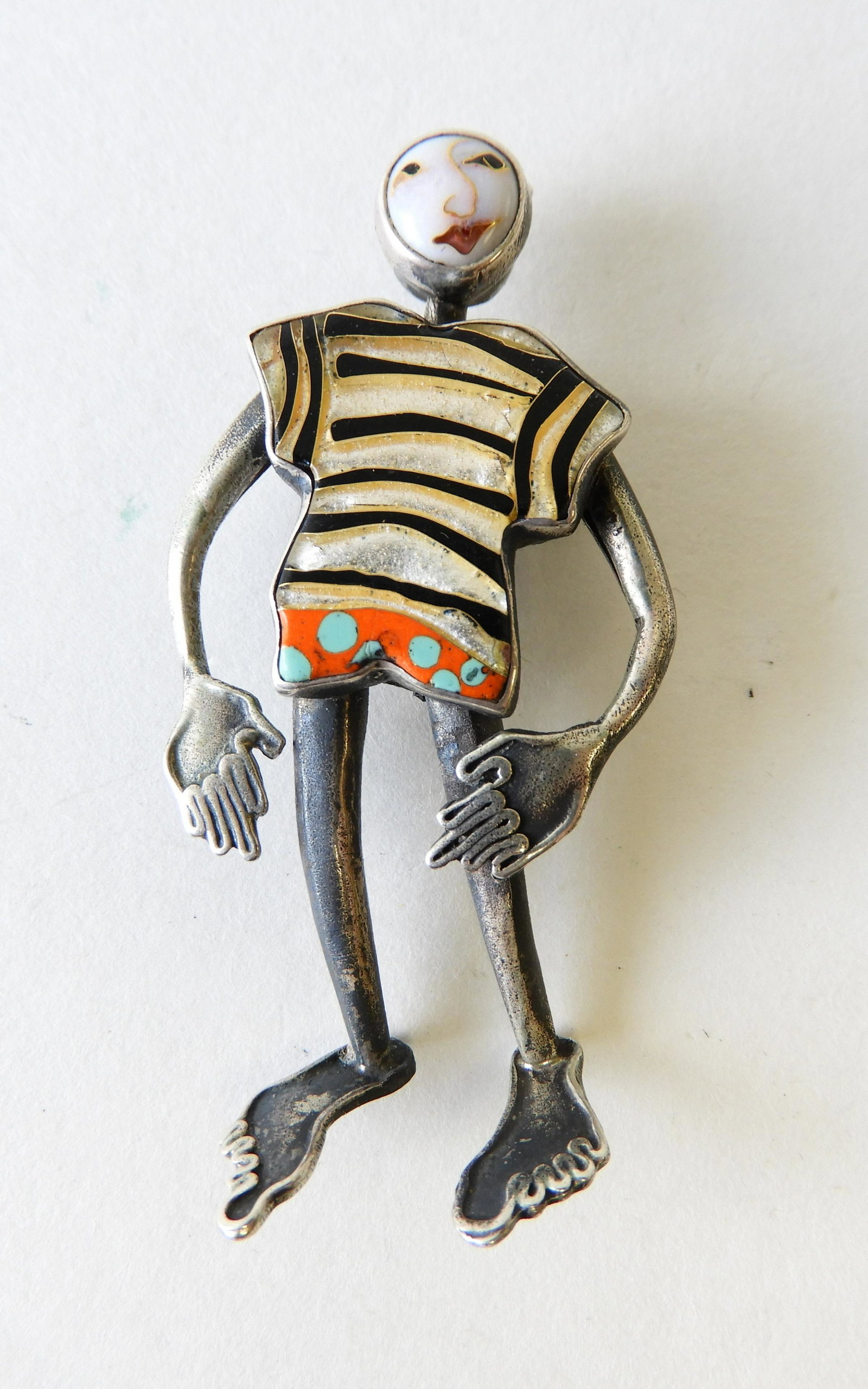 Sterling Silver & 24K Figure Brooch: 2.5" tall figural brooch composed of sterling silver and 24k gold wearing a striped enamel shirt. Back marked Kristin Holeman Sterling Silver + 24K. Property from the estate of Rosalie Coe Weir