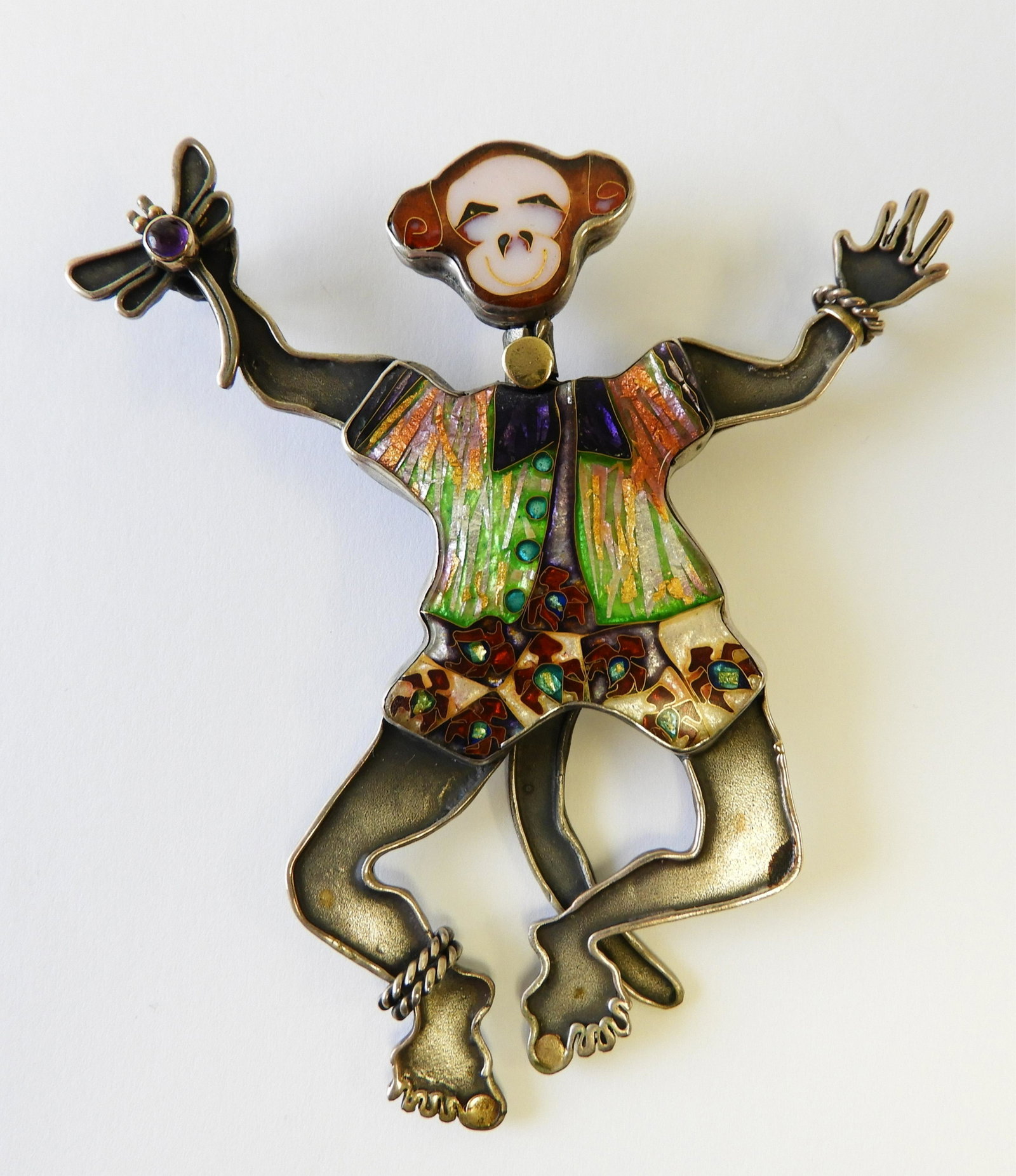 Dancing Monkey - Sterling, 22k, 24k: 3.5" tall dancing monkey made of sterling silver, 22k gold, and 24k gold with a cloisonne enamel face and outfit. Holding a small dragonfly with cabochon amethyst body in his proper right hand. Tail m