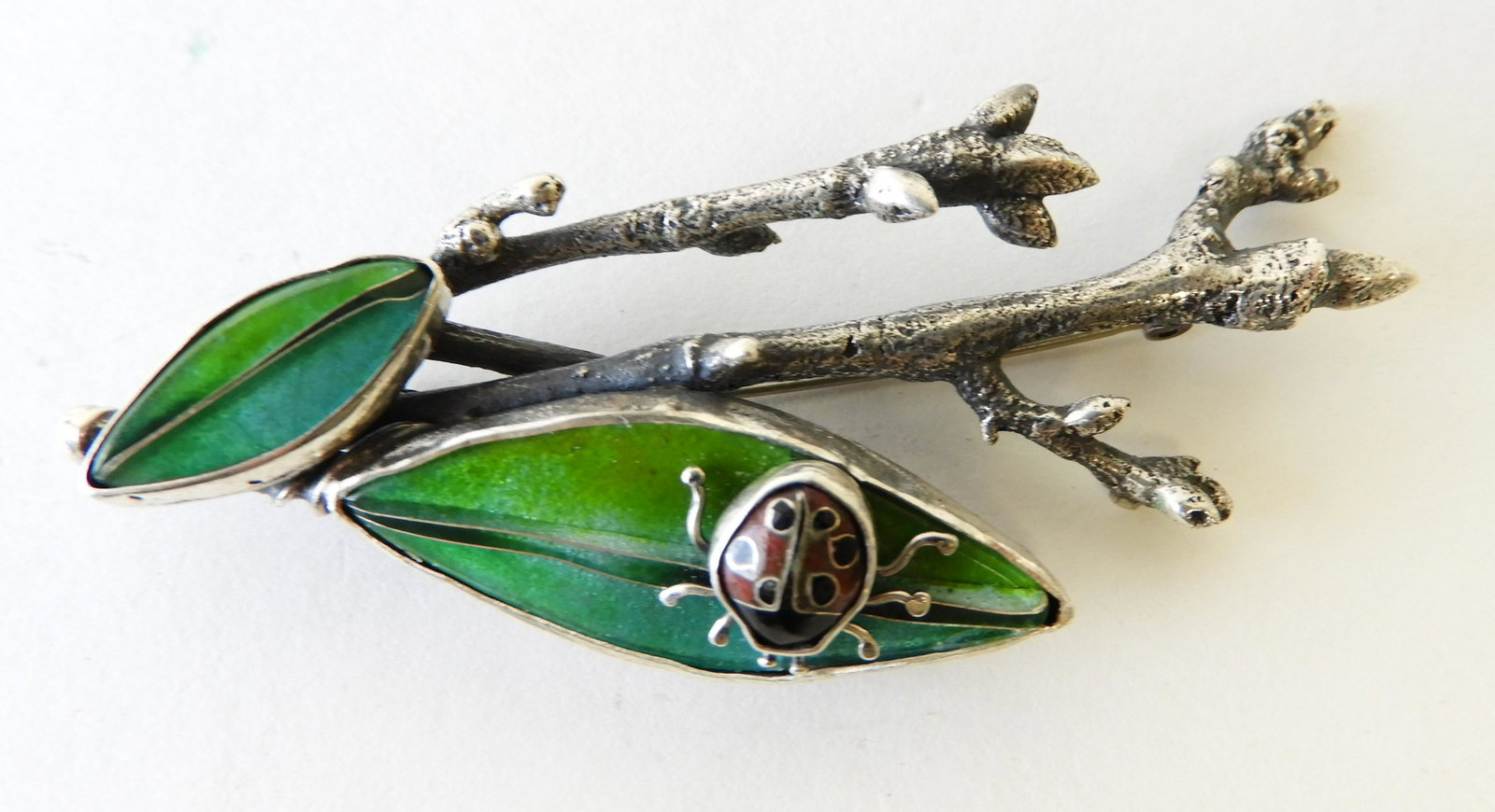 Enamel Ladybug on Leaf Brooch: Sterling silver branches holding cloisonne enamel leaves and lady bug. Signed Kristin Holeman on back and marked sterling silver. 3" wide. Property from the estate of Rosalie Coe Weir