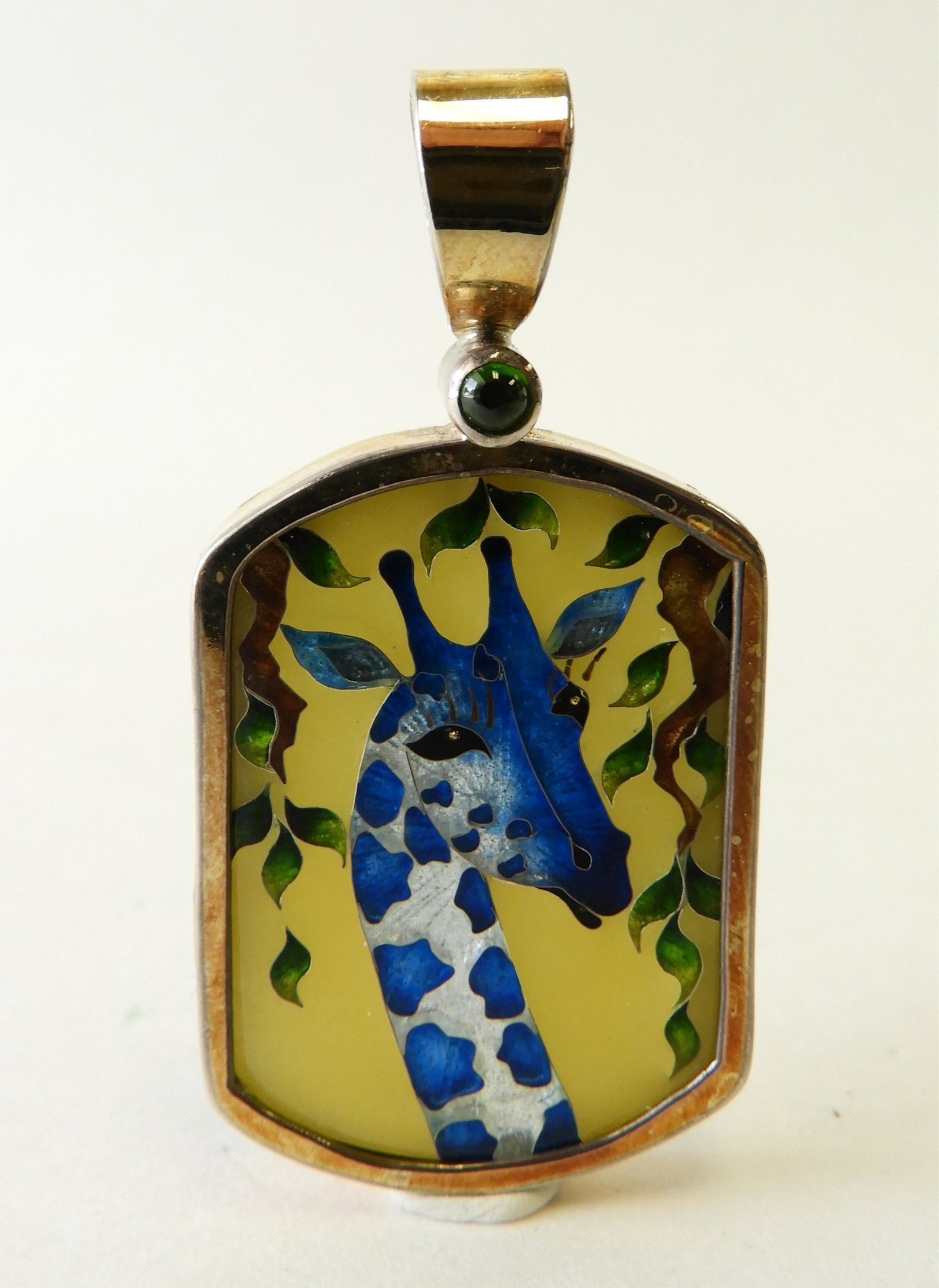 Cloisonne Enamel Giraffe Pendant: Cloisonne enamel giraffe pendant set in sterling silver, 18k gold and 22k gold by Tricia Young. Stamped as such on back and signed Tricia Young. Pendant is 2" long. Gross weight of 20.2 grams Property
