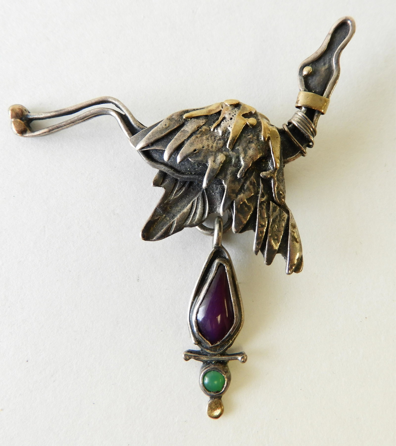 Gold & Sterling Egret Brooch: Sterling silver egret brooch with 22k gold elements designed by Kristin Holeman. Signed and marked on back. Hard stone drop detail -- larger stone is amethyst. 2.5" x 2.75" Property from the estate of