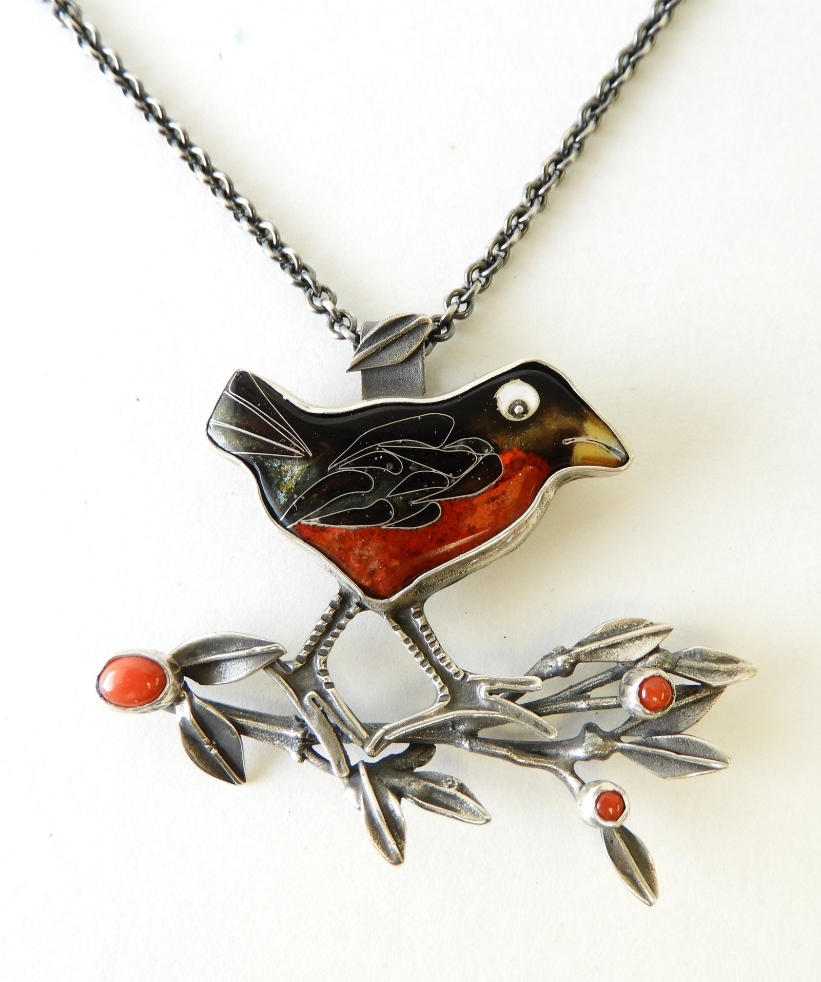 Sterling & Enamel Robin Necklace: Sterling silver pendant in the form of a robin on a tree branch. Robin has red & brown cloisonne enamel body. Three hard stone details within the leaves. Signed Kristin Holeman on the back. On a 22" c
