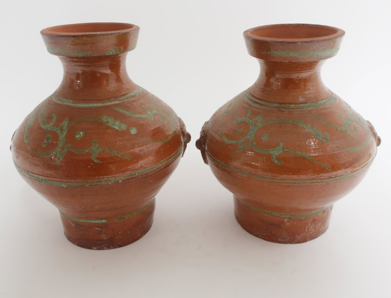 Two Matching Han Style Terracotta Hu Vases: Nearly matching terracotta vases of the typical Hu form and ochre glaze of the 1st-3rd century Han Dynasty. Both have rough green glazed lines decorating the body reminiscent of abstract Han dragon mo