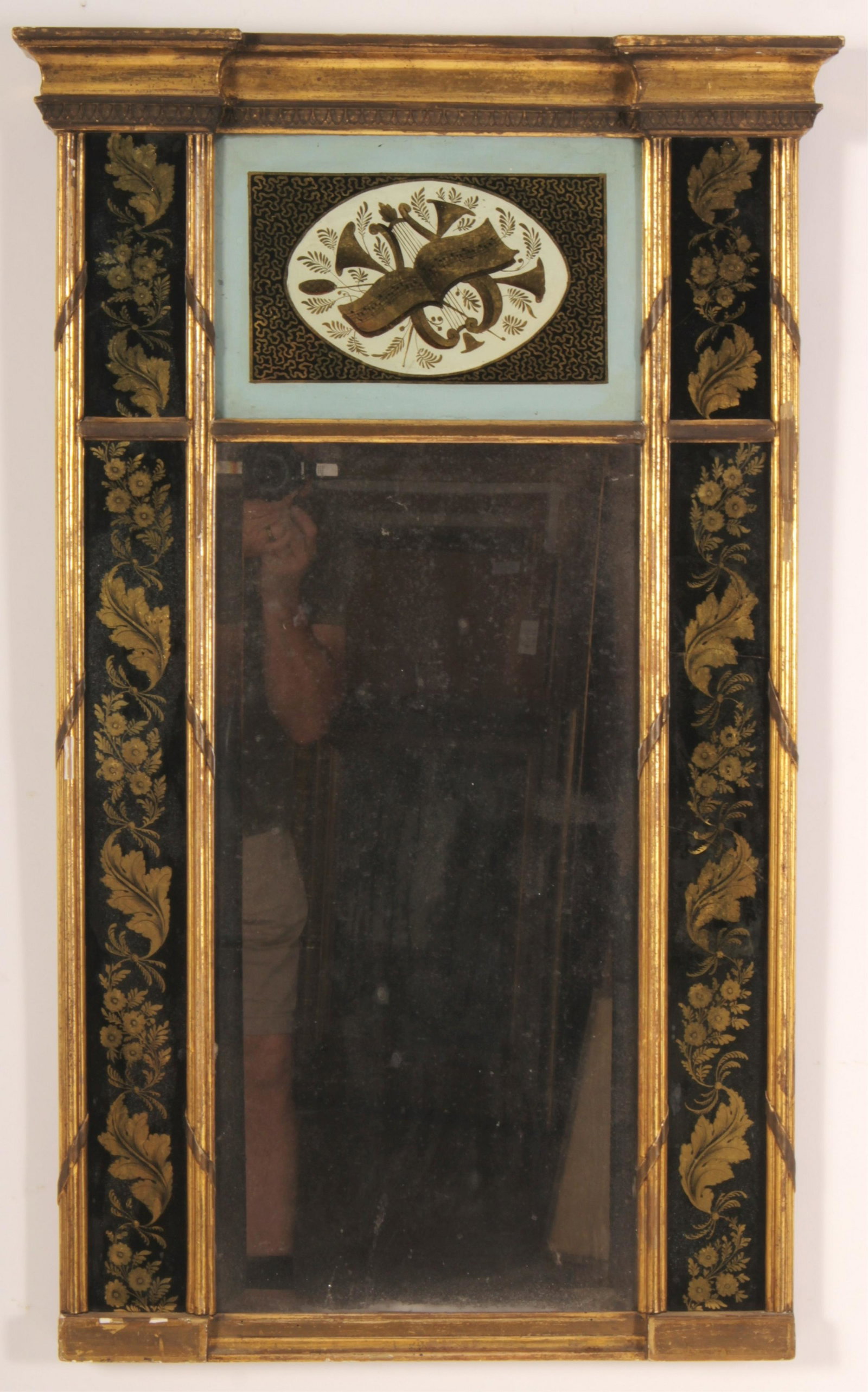 19th c. American Giltwood and Eglomise Mirror: Federal/Sheraton period, c. 1815, top eglomise panel with classical trophies, side panels with vertical foliage and blossoms, original gilding and mirror plate 38" H x 23" W Litchfield Auctions is hon