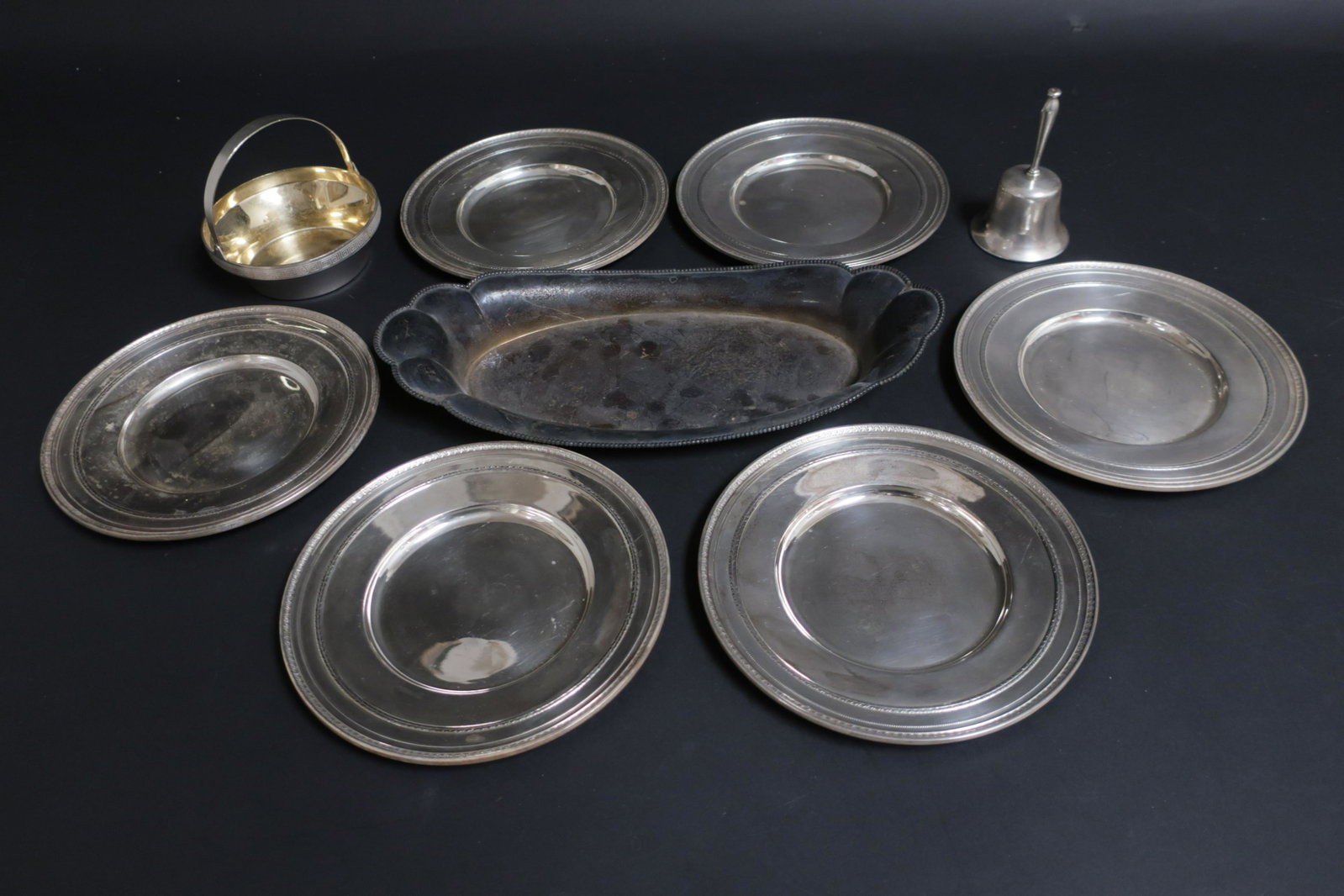 Group of Sterling Silver Dishes: 6 bread plates, tray, bell and small basked. .916 standard. 49 ozt. Very good with serious tarnish to tray and a few tiny dents and scratches to other items Property from a private collection - East 6