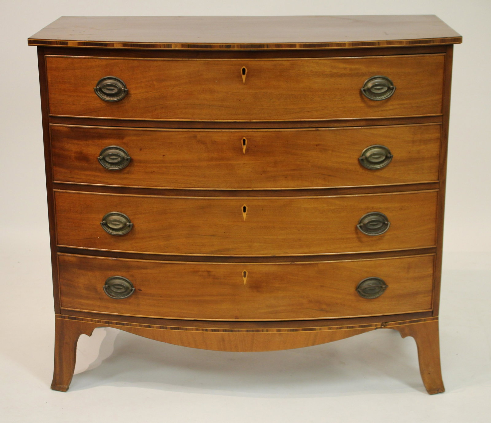 Mahogany Bowfront Chest of Drawers, 19th C: Pine secondary. Four typical size drawers with beaded edges; inlaid escutcheons; banded bottom, top edge; oval bail pulls. 37"H x 41.25W x 21D (BBRA10274)(JP)