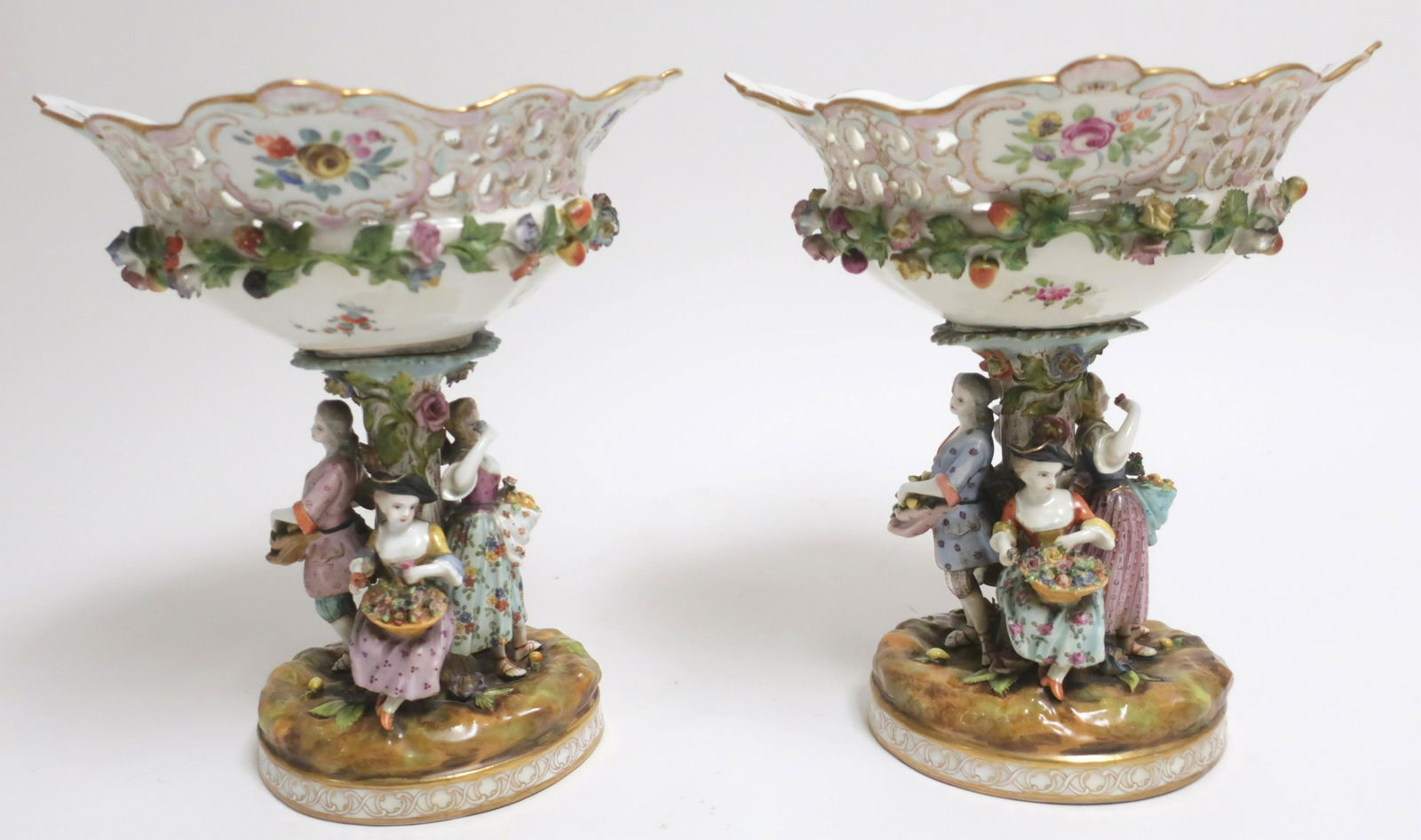 Pair Carl Thieme Potschappel Porcelain Compotes: Late 19th C., in Meissen style, reticulated baskets, figural supports, stylized crossed swords centered by a T mark. 11.75 H x 10.5 W x 9.75 D Property from the Estate of Madeleine Deutscher, Sutton P