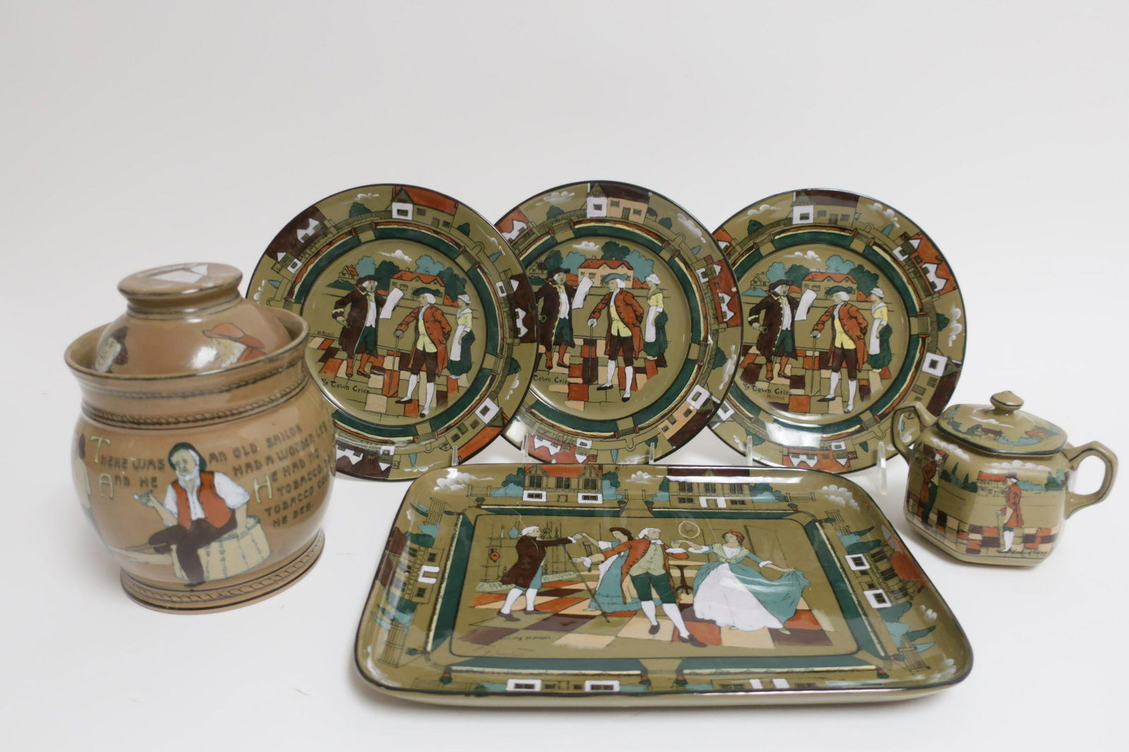 6 Deldare Ware Buffalo Pottery Pieces: Buffalo Pottery Deldare Ware Old Sailor Tobacco Humidor 1909, Sugar Bowl 1909, 3 Ye Town Crier Plates 1908 along with a Rectangular Dressing Tray Dancing Ye Minuet, all artists signed Tray 9 x 12 to S