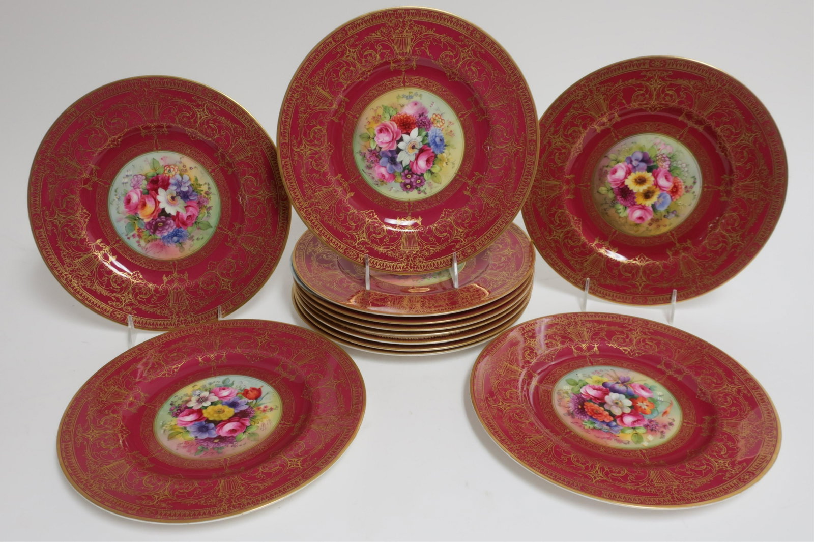 12 Royal Worcester Cabinet Plates - Hand Painted: A Set of Twelve Royal Worcester Cabinet Plates, England, c. 1925, each with central polychrome hand-painted flower spray, most signed "E. Phillips," one signed obscurely, one unsigned, the body maroon