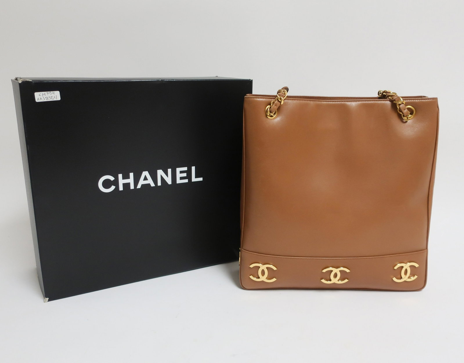 Vintage Chanel Shoulder Tote: Carmel smooth calf leather exterior with Chanel emblems around bottom. Font exterior slip pocket, two interior zip pockets. Double chain/leather handles. Made in Italy. Hologram sticker 2XXXXXX (1991-