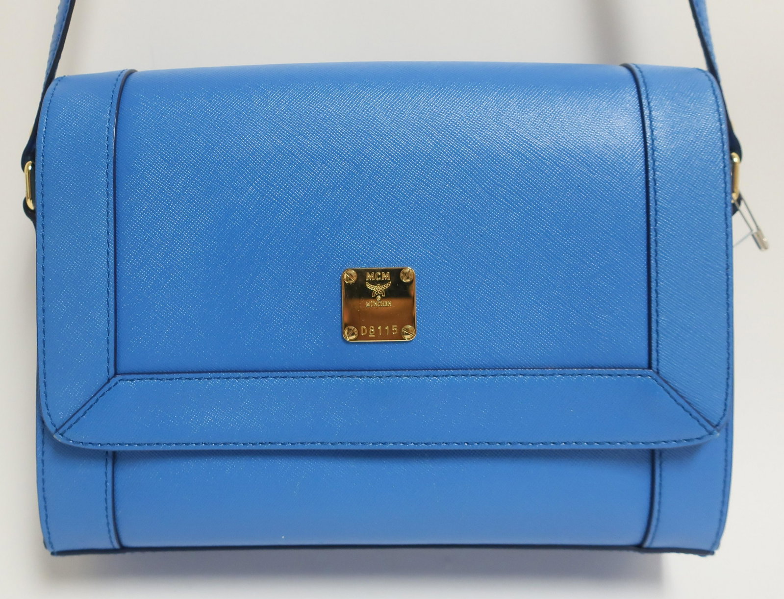 MCM Square Flap Shoulderbag: Electric blue grained leather with light blue logo'd interior. Dual compartment interior with two zip and two slip pockets. Front snap closure. Product code D8115 10" x 8" x 2.5" 21" shoulder drop, ad