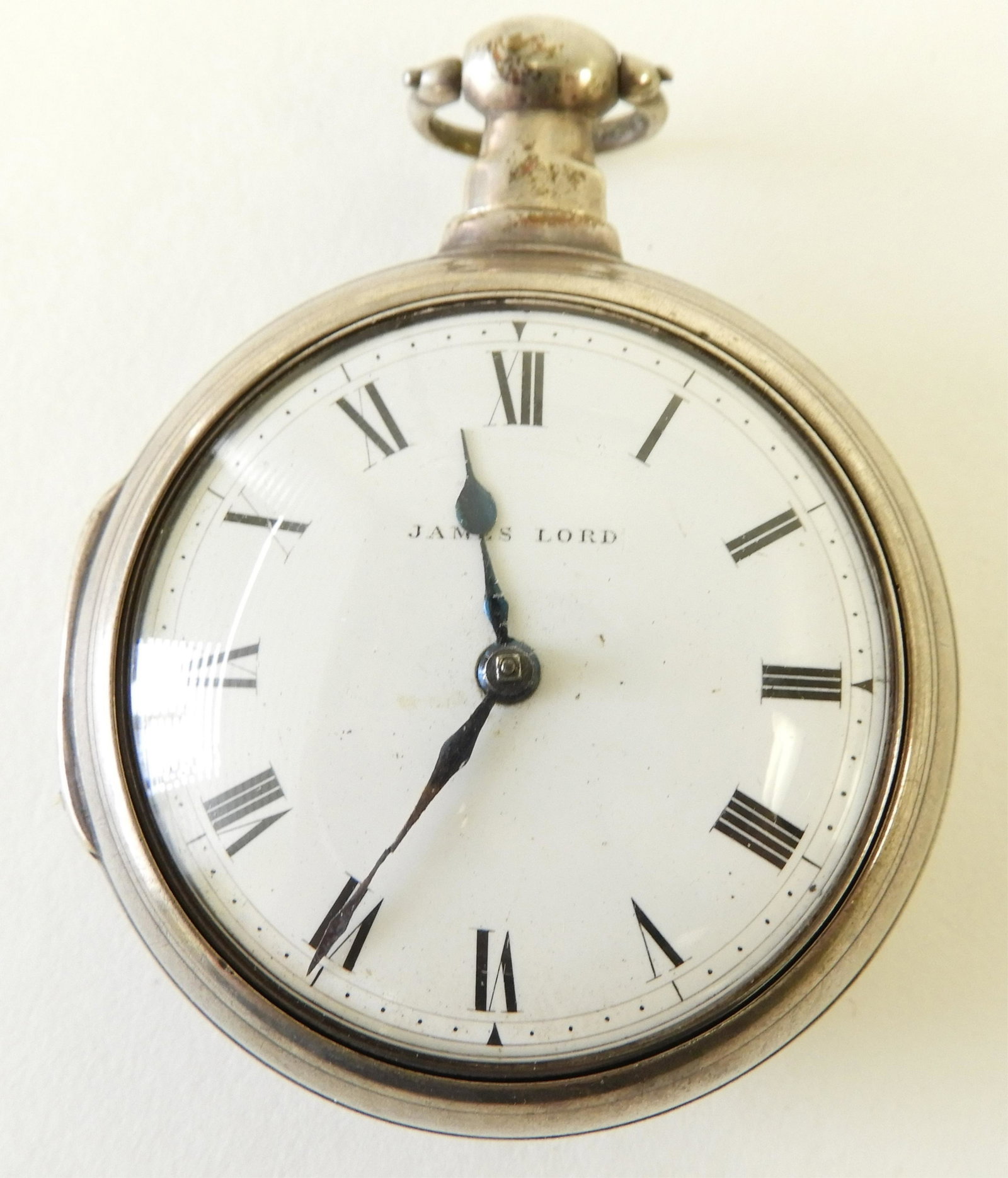James Glover Sterling Silver Pocket Watch: Open face paired sterling silver inner and outer cases, white enamel dial stamped “James Lord”, black Roman numerals, outer case having retailers papers and Chester hallmarks and dated 1810, 43mm 