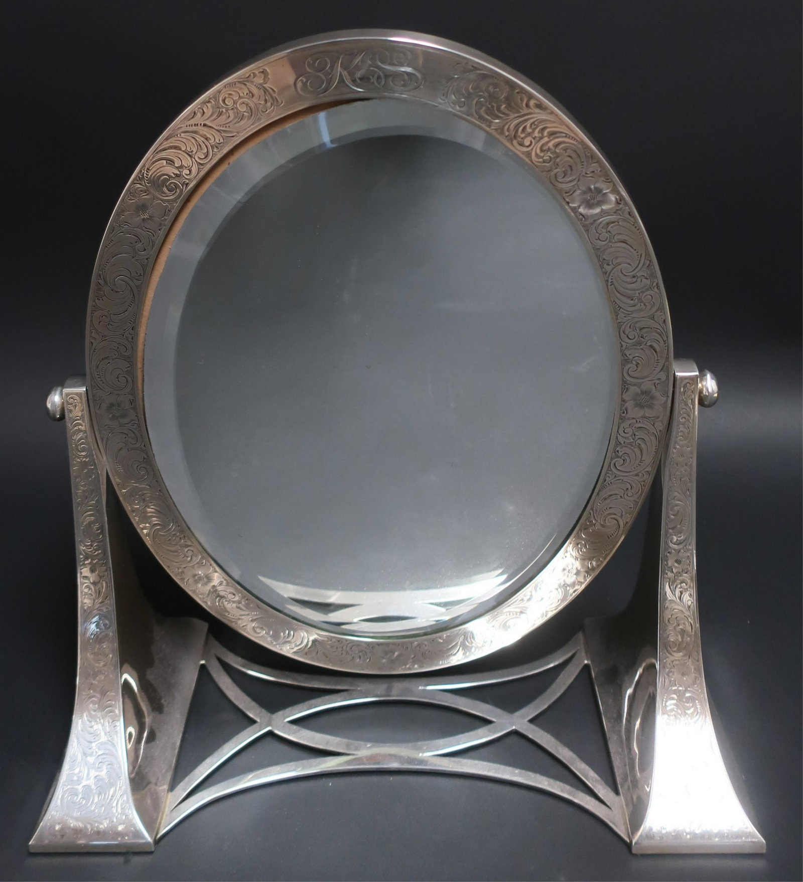 Lebkuecher & Co. Sterling Dressing Mirror: Lebkuecher & Co. Sterling Silver Oval Dressing Table Mirror, on adjustable stand, beveled edge, monogram, bright cut scroll & flower decoration (SPAR2436)(WT) Dimensions: 15" H x 13 3/4" W x 7" D Prop