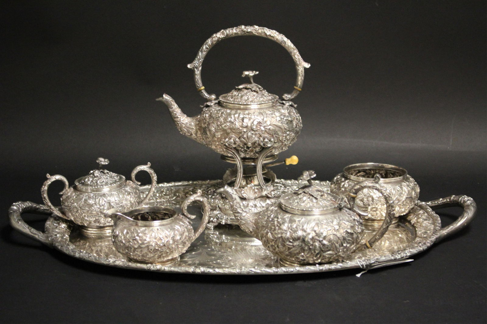 Samuel Kirk 7 pc Sterling Repousse Tea Set c. 1910: A seven piece Sterling Silver tea set by Baltimore's premier silversmith, including its matching tray, heavily repoussed and hand-chased floral decoration, flower bud finial, marks for S. Kirk Son Co.