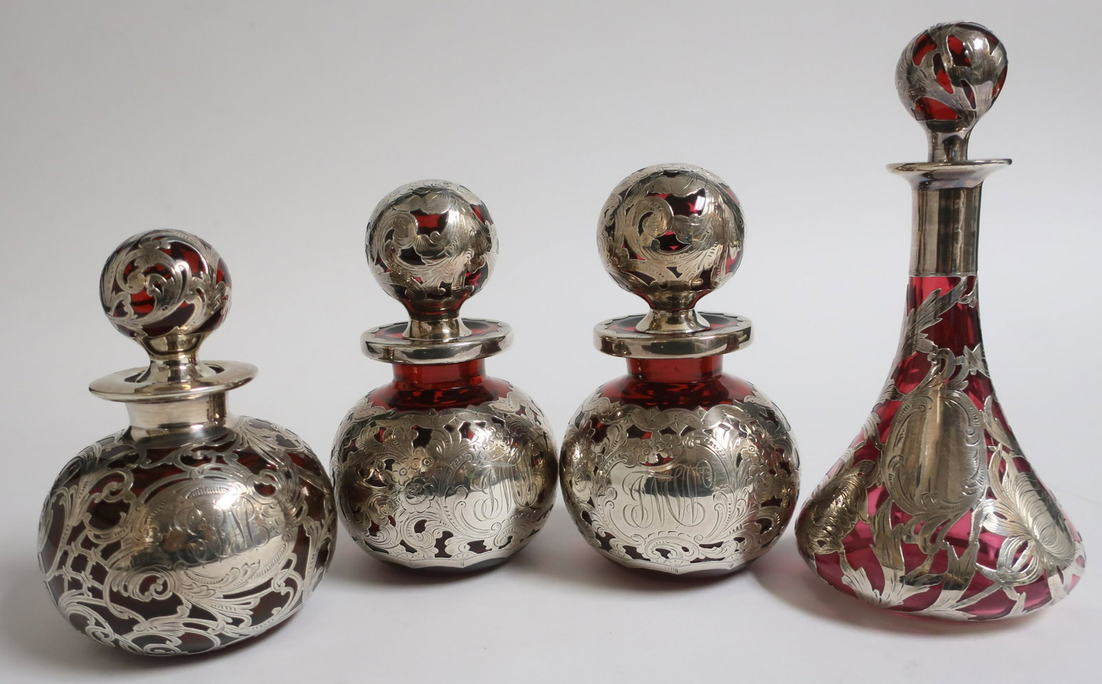 4 Silver Overlay & Ruby Glass Bottles: 4 Sterling Silver Overlay Ruby Red Glass Perfumes/Bottle, includes a pair Gorham licensed S684, 6 1/4" H x 3 1/2" dia. monogrammed, ring of white to bottoms, small chips to stopper ends. Alvin R3088 t