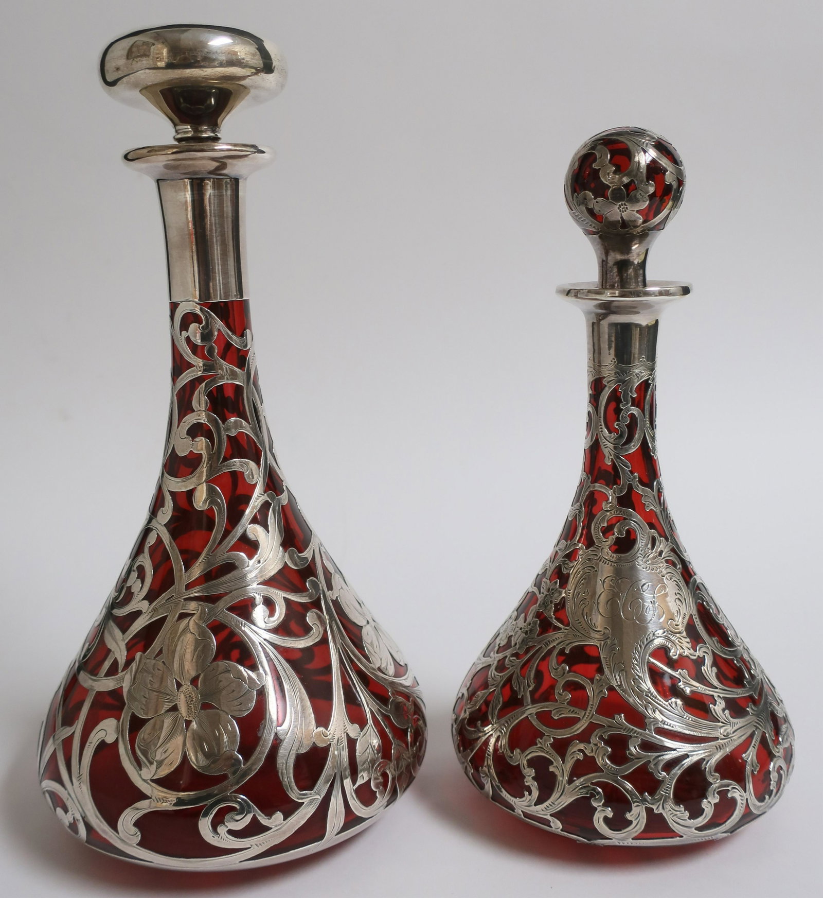 2 Lg Sterling Overlay & Ruby Glass Items: 2 Large Sterling Silver Overlay Ruby Red Glass Bottles/Decanters, 4.34 lb., trumpet form, comprises: Alvin E110PT 10" H c 4 3/4" dia., very good except chipped stopper, monogrammed; sterling silver de