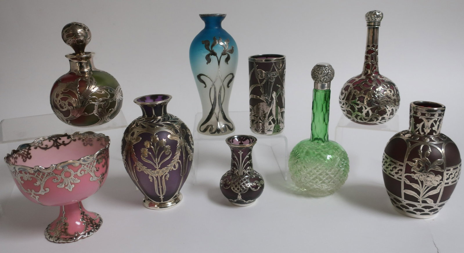 9 Silver Overlay & Glass Items: 9 Sterling Silver Overlay Art Glass Vases, Bottles Perfume & Cup, one with herons, one multi colored glass, others green, purple, pink marked Belleek (?) (9 pc.) (SPAR2443/9)(WT) Dimensions: 3 1/4" H 