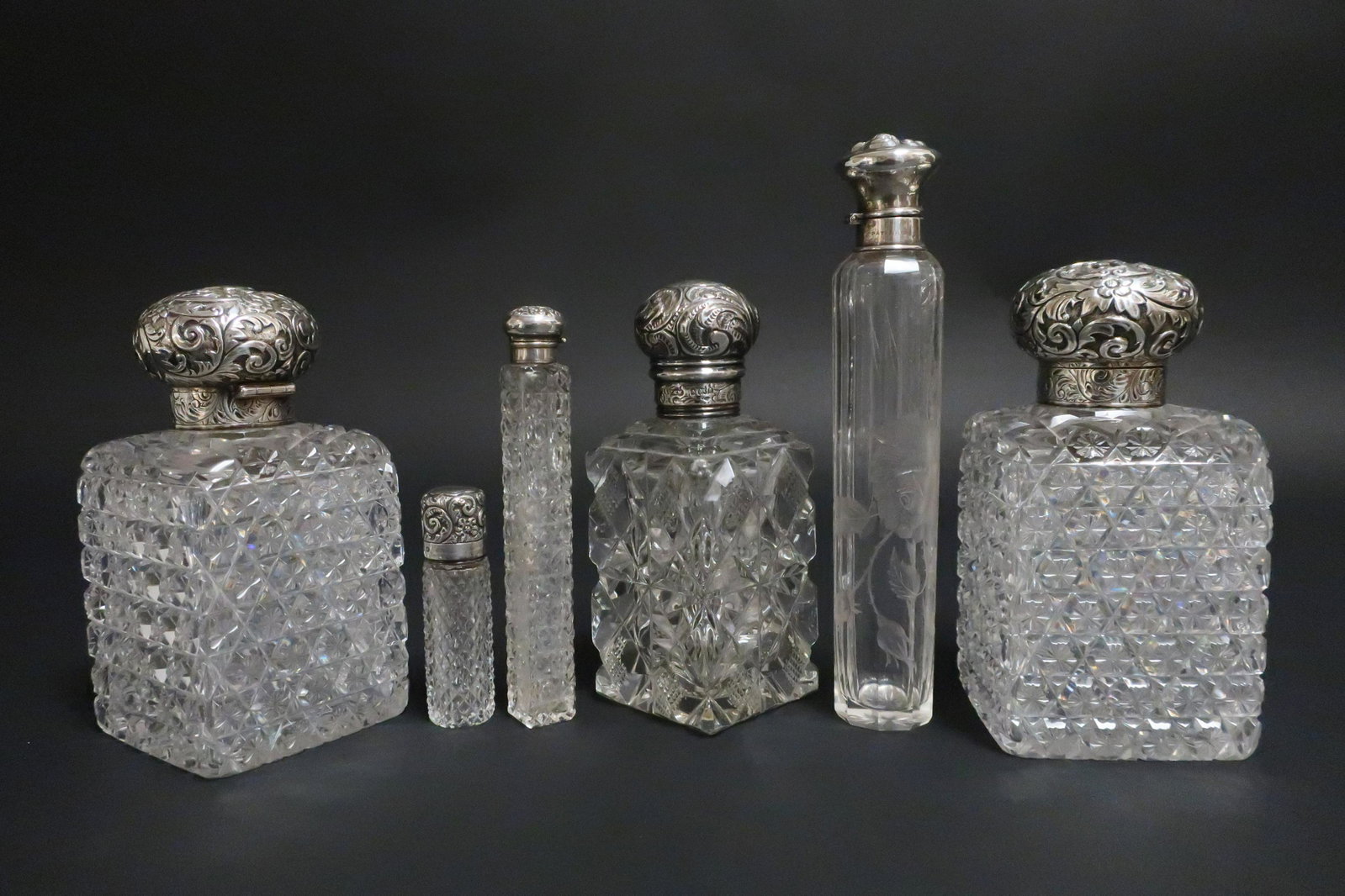 6 Cut Glass Sterling Silver Top Perfumes: 6 Cut Glass Sterling Silver Top Perfumes, most with English silver marks, includes large pair with repousse figure of a man and woman, glass cut with snowflakes (6 pc.) (SPAR2419/6)(WT) Dimensions: Pa