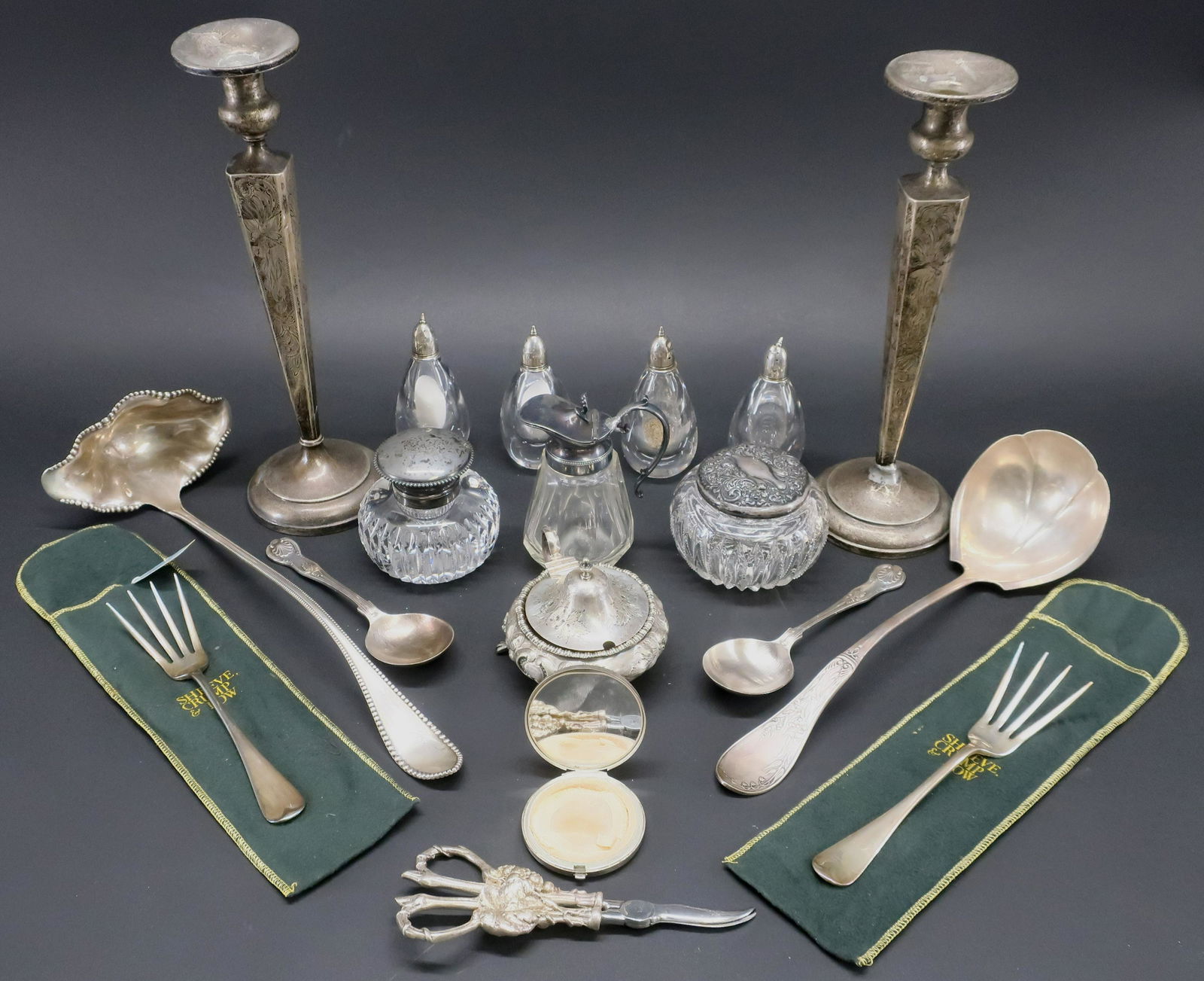Small Group of Sterling & Silver Plate Items: Pair of weighted sterling candlesticks, cut glass inkwell, powder jar, four salt and peppers (all with sterling silver tops), silverplate mounted drum, syrup jug, compact, and two ladles. Dimensions: