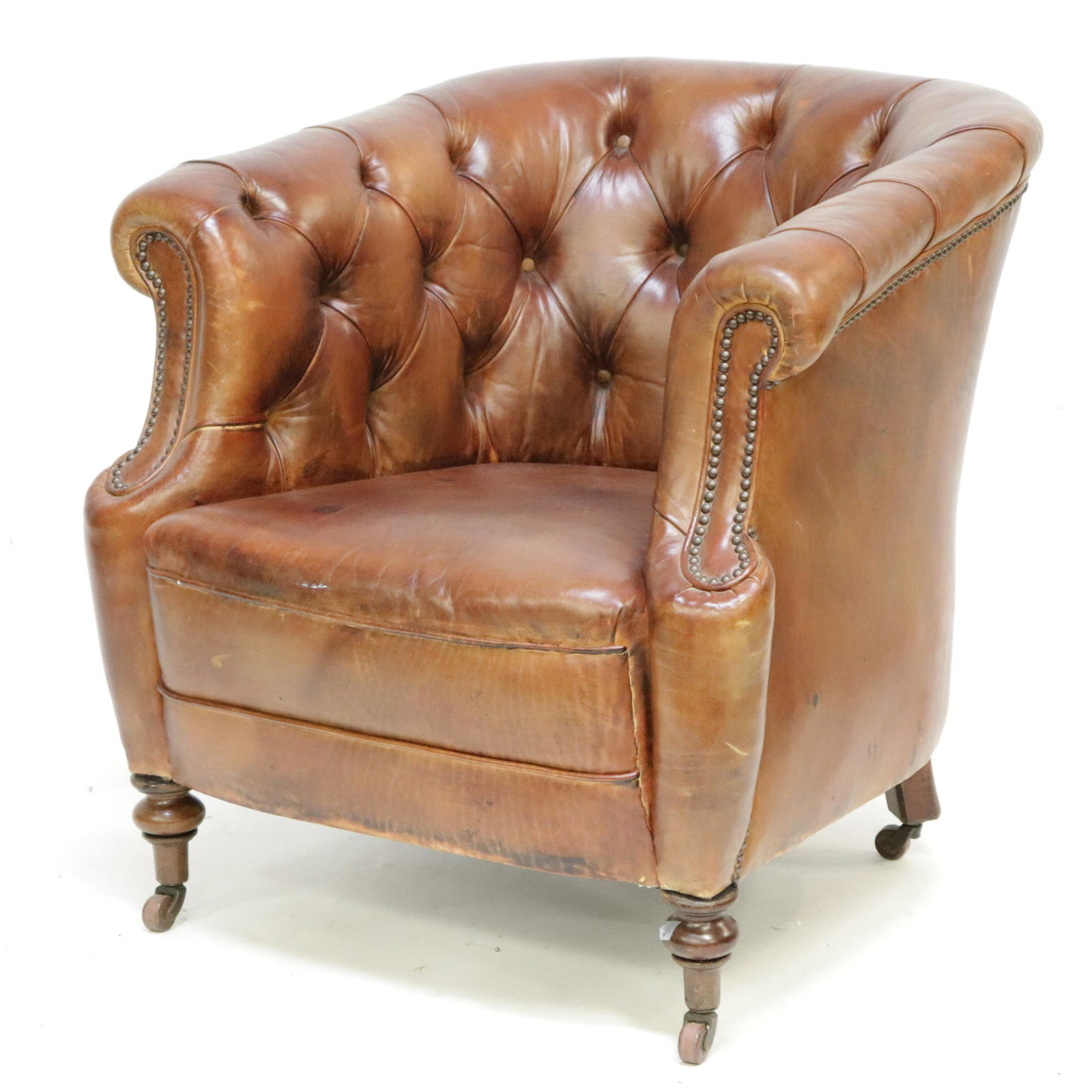 Victorian Mahogany & Brown Leather Club Chair: On porcelain casters. Dimensions: 30.75 H x 29.5 W x 35 D Property from a Greenwich, CT home (ELB519)(MS)