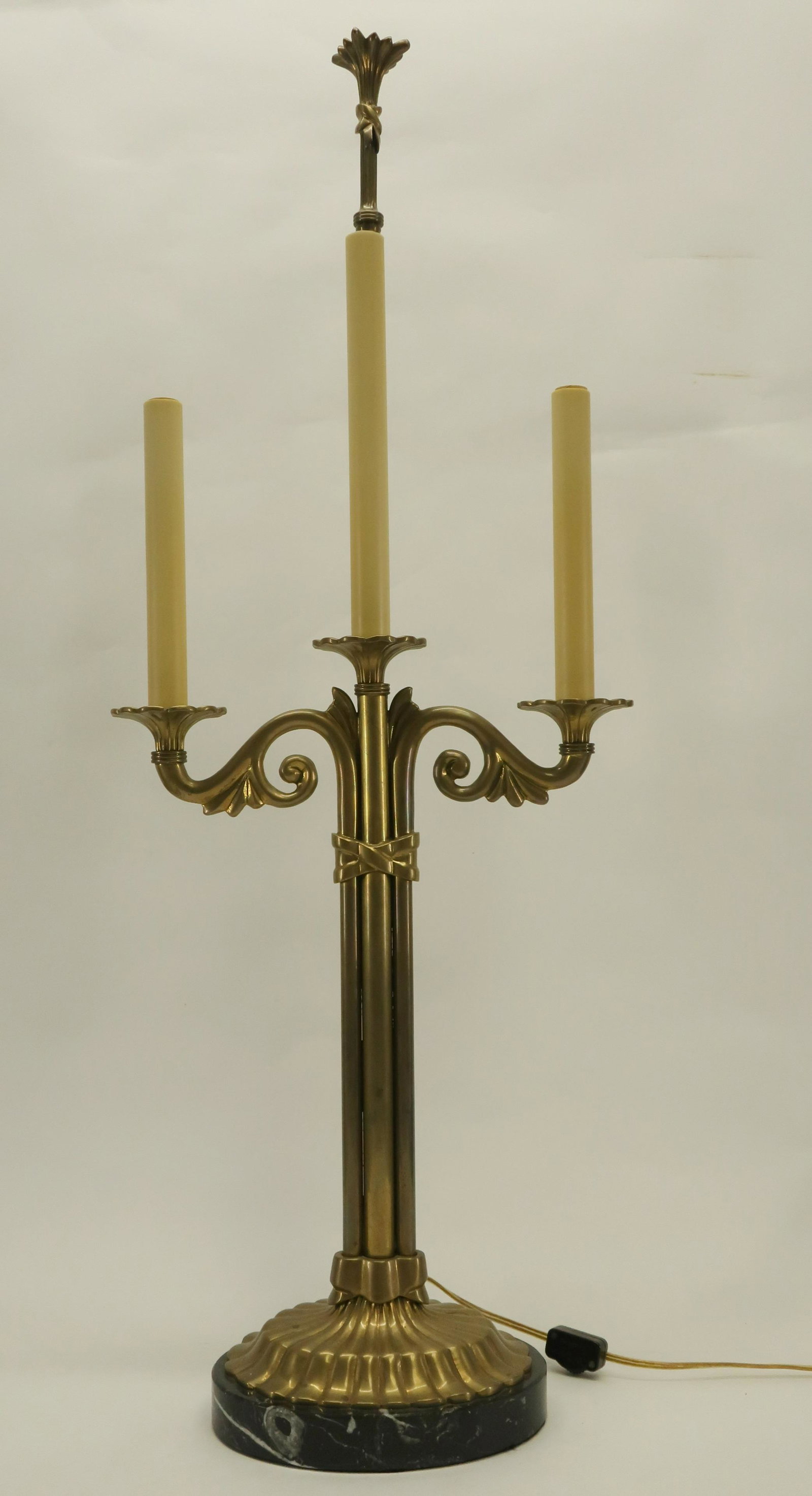 Two-Light Candelabra Form Chapman Table Lamp: C1994. Brass with oval marble base. Tall center sleeved standard with decorative finial. Oval marble base. Candle sleeves. In-line switch. Dimensions: 33"H x 12.75W Oval base 8 x 6 Property from a Lit