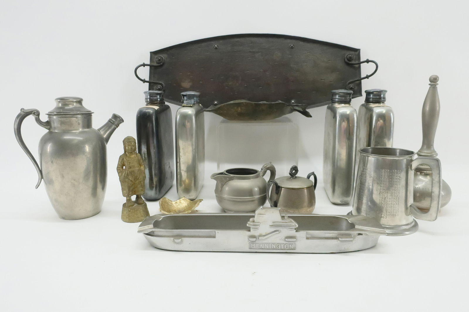 Metal Lot, incl. Arts & Crafts, Flasks, etc.: Metal Lot, includes aircraft carrier form aluminum ash tray, Arts & Crafts tray, gilt figure of a Dutch boy, flasks and more Dimensions: Carrier 13 1/2" L, Tray 21" L, Flasks 8 1/2" L (EDEL6196/lot)(W