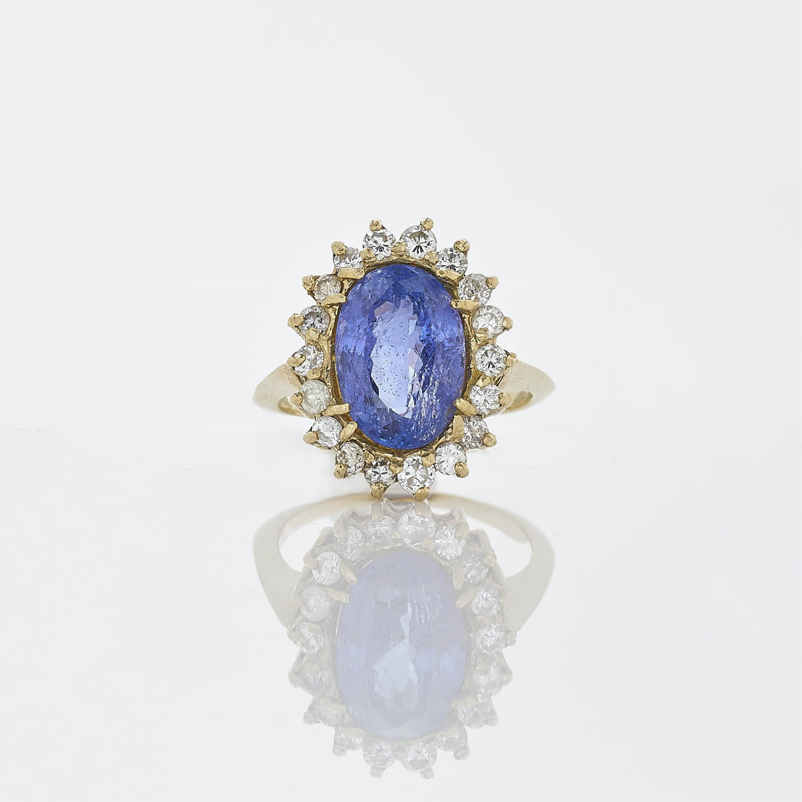4.11 ct Tanzanite & Diamond Dinner Ring: Central prong set bluish violet tanzanite weighing ~4.11 ct surrounded by 18 round brilliant cut diamonds weighing ~0.94 cts. Set in 14k yellow gold. Gross weight of 4.9 grams. Dimensions: Size 7.5 Pr