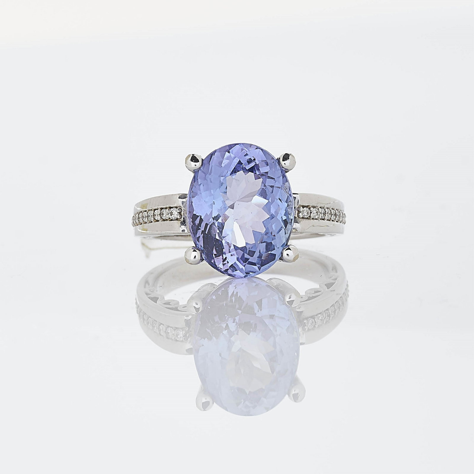 6.85 ct Tanzanite Ring: Central prong set bluish violet tanzanite measuring 13.01 x 10.32 x 9.67 mm, weighing 6.85 ct. Accented by 28 round diamonds measuring 1.03 mm, set in 14k white gold. Dimensions: Size 7.25 Property fr