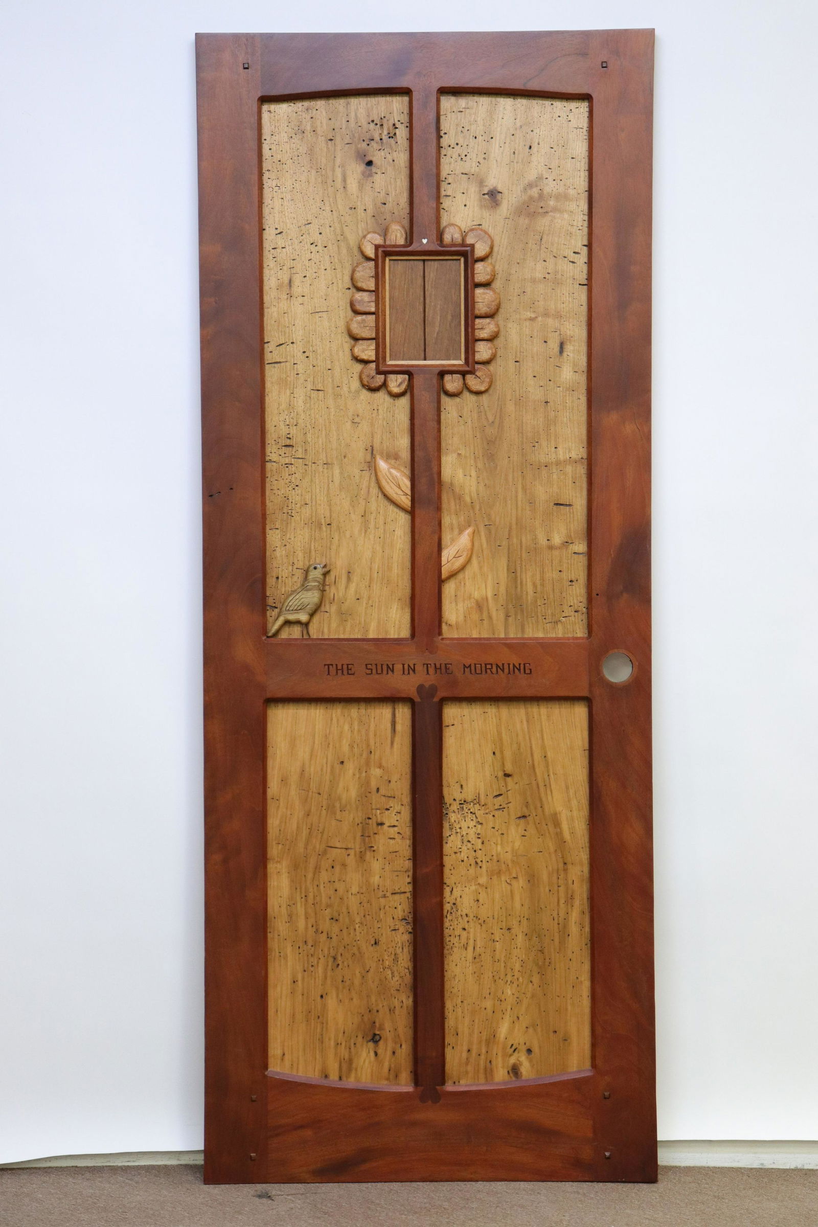 Tommy Simpson Designed/Decorated Interior Door: L20C. Mixed woods. Applied shaped bird and flower motif with latched square visitor announcement door as part of flowerhead. Raised panels with chamfered frame. Carved and painted and M.O.P. inlaid st