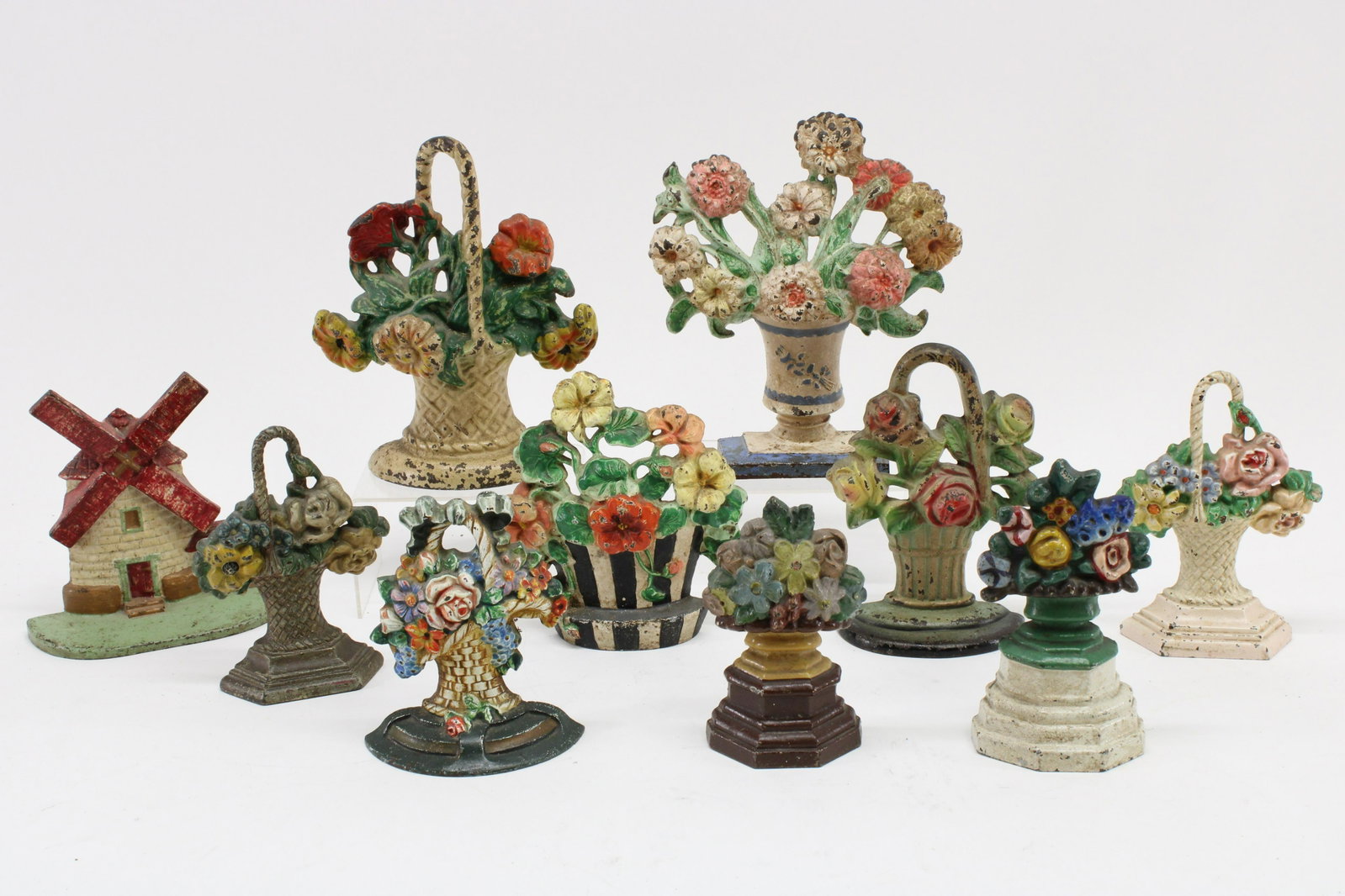 10 Cast Iron Doorstops; floral baskets, windmill: 10 Cast Iron Doorstops, 9 colorful floral baskets and one windmill Dimensions: Largest 9 3/4" H x 8 1/2" W, Windmill 7" H x 7" W Property from the Estate of C. Carter Walker Jr, Washington, CT. (CCWJ8