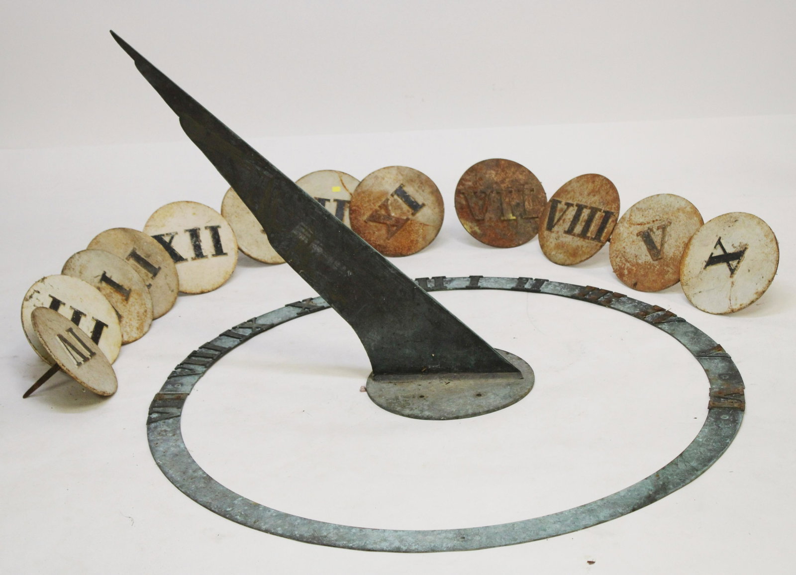 Bronze & Cast Iron Sundial Parts: Bronze & Cast Iron Sundial Parts, consisting of a bronze gnomon and partial set of the hours and 12 cast iron roman numeral hour markers Dimensions: Gnomon 29" H x 40" L x 12" Dia., Cast iron numerals