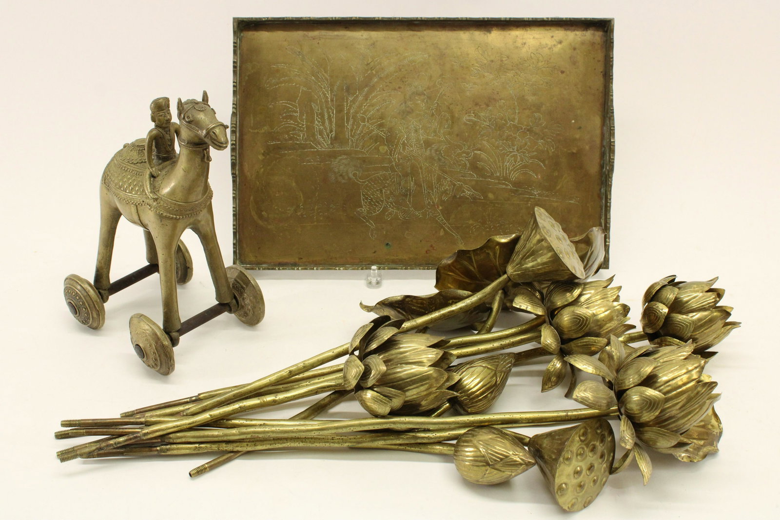 Decorative Brass Group: Stemmed Flowers, Camel: Lotus flowers, pods, lily pads all on threaded stems (12 total). Camel on wheels (India). Rectangular tray (China). Dimensions: Flowers 15" to 23H Camel 12H Tray 12 x 18 Property from a Litchfield hom