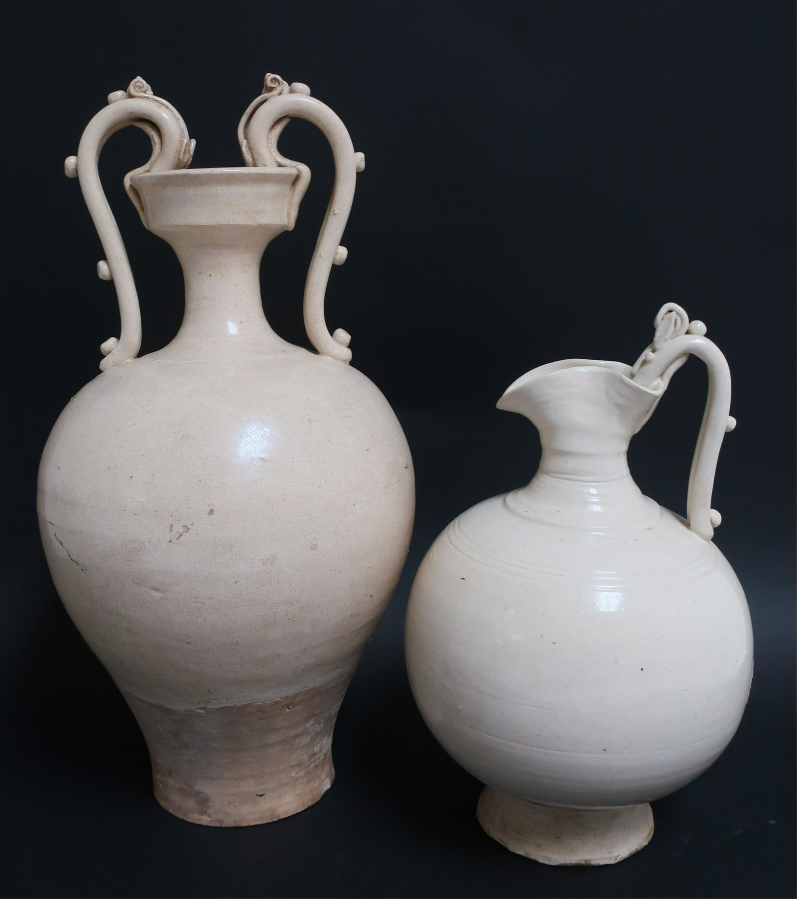 Two Tang Dragon Handle Vessels: Two nice examples of the narrow necked globular vases with knobbed dragon handles curving into the mouth. The taller amphora has two handles and the smaller ewer has one handle opposite a spout formed