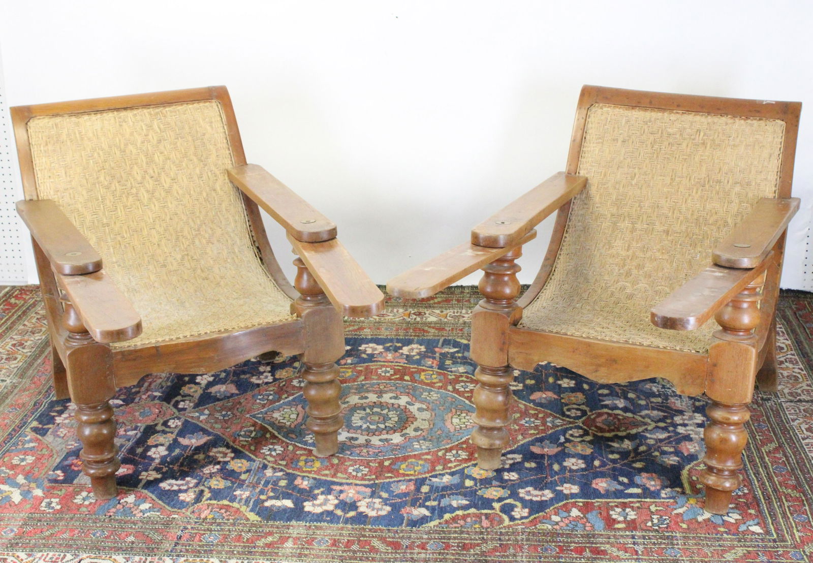 Pair British Colonial Caned Plantation Chairs: Continuous caned back to seat. Pivoting leg rests extended arms. Heavy scale turned posts. Dimensions: 43"L x 27W x 31H. Arm extension 27L. Front seat height 15.5 Property from a Northwest, CT collect