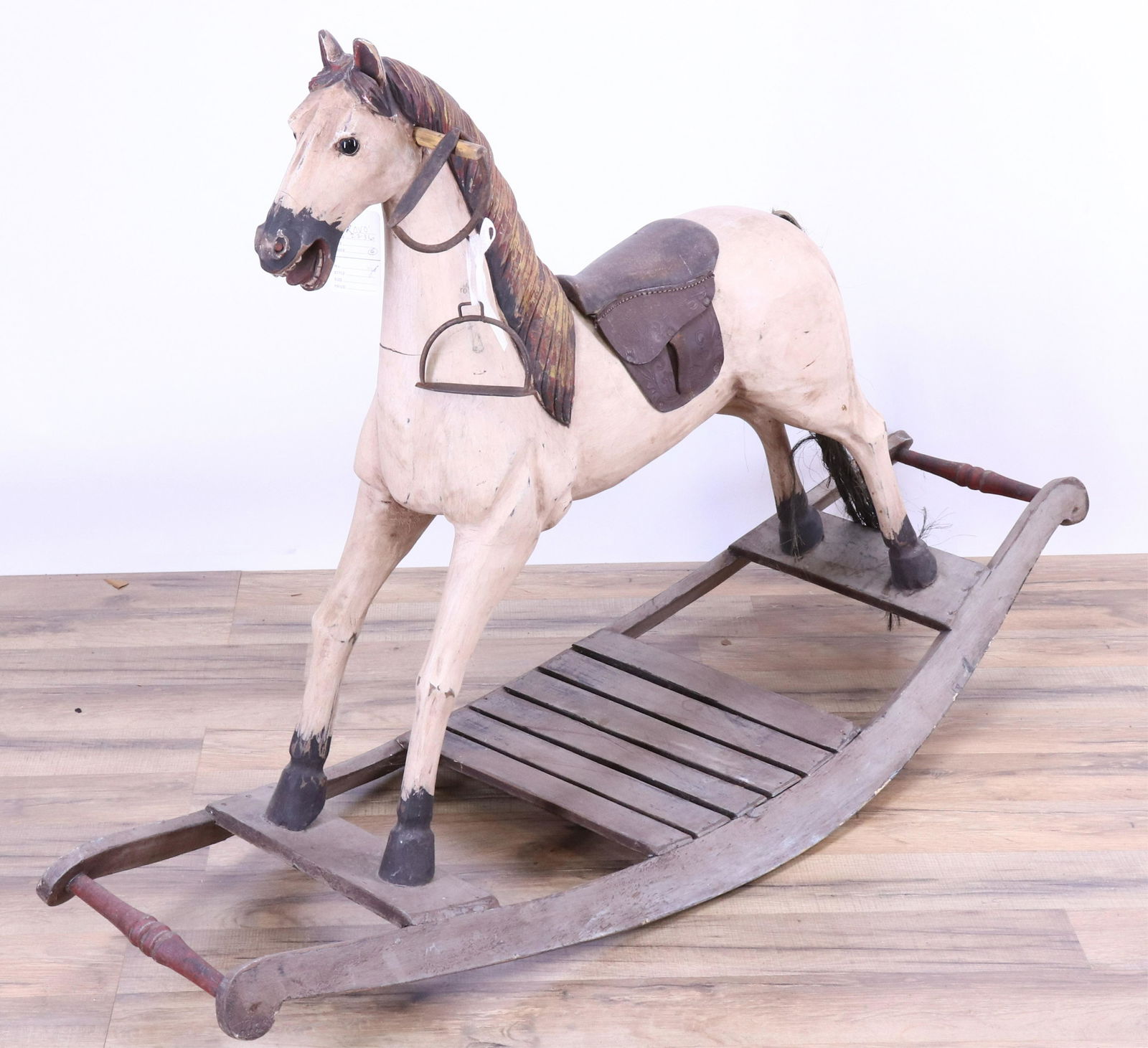Vintage Painted Wood Rocking Horse: On ellipsed rocking platform. Well carved/shaped legs and detailed mane texture. Leather saddle. Has two metal stirrups. (ROVO2236)(JP) Dimensions: 48"L x 32H x 16.5W at platform. Property from a Litc