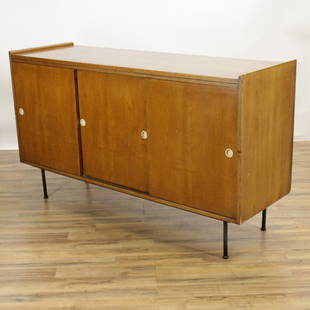 Landstrom Furniture Credenza: Honey-maple in color. Three sliding doors. Right side interior reveals three vertical drawers with hand pull shaped cut-outs. Left side with single adjustable shelf. black painted metal legs. (JAMC119