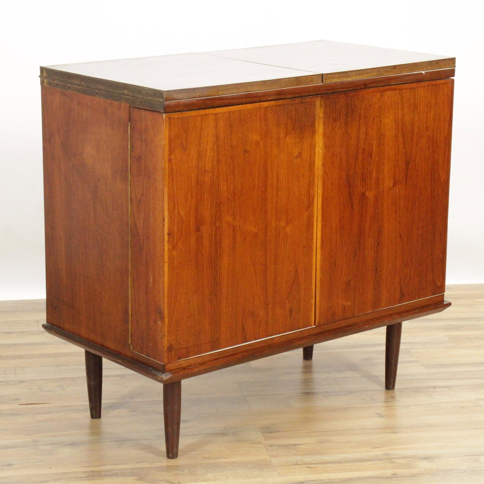 MCM Dry Bar with Fold-Over Top, Shelved Doors: Swing-out piano hinged shelved doors that support piano hinged fold-over top. Touch latch doors. Interior fluorescent light. Teak or walnut veneer, contrasting faux wood laminate top, white painted in