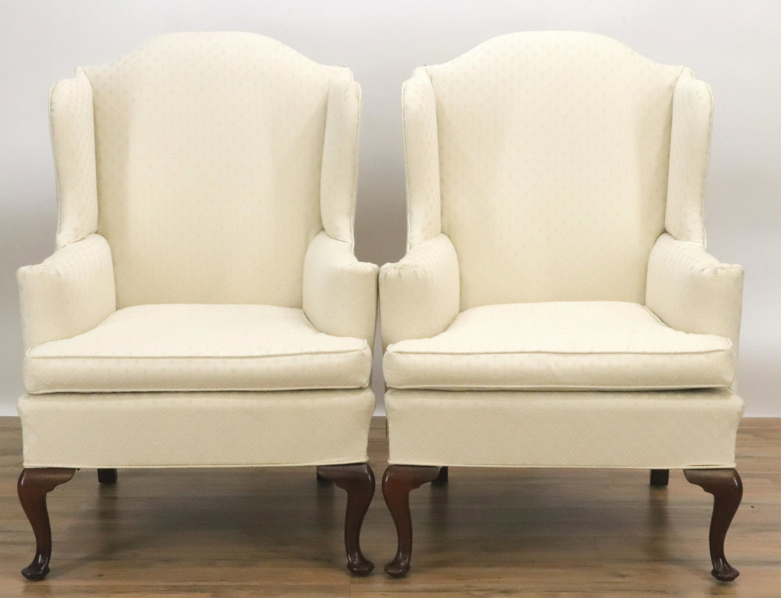 Pair of Queen Anne Style Wing Chairs: Textured pattern cream colored fabric and welting. Relatively new upholstery fabric. Dimensions: 44"H x 31.5W x 33 deep overall. Seat is 20H x 22 deep Property from a Litchfield, CT home (BMAS91/2)(JP