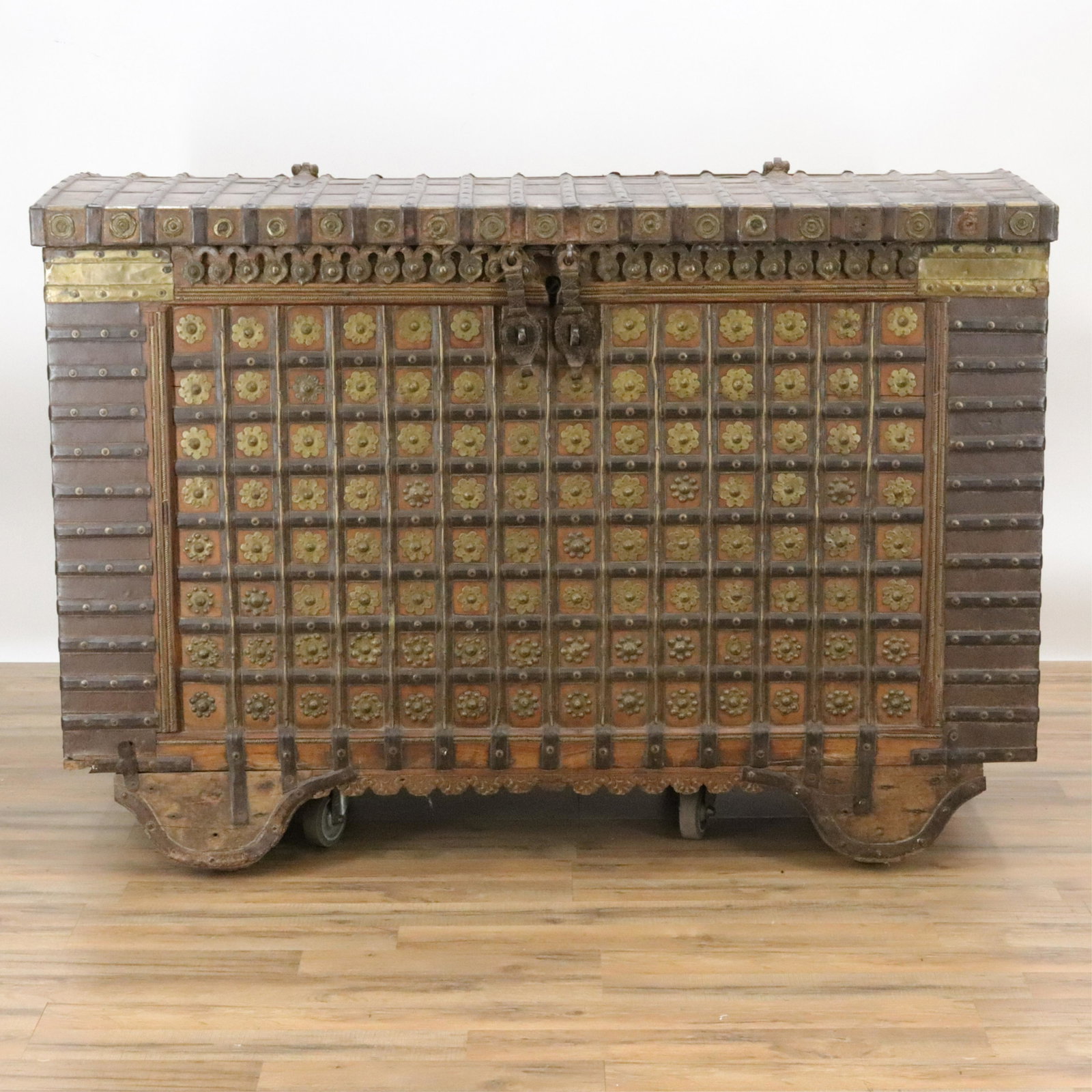 Massive Wood And Iron Damchiya Dowry Chest: Domed top coffered front with floral studs. Iron ribs and bail handles. Heavy drop latches. Interior with side tills. Attached wood wheel and axle trolley. "HANDCRAFTS DELHI" stamp on back. Dimensions