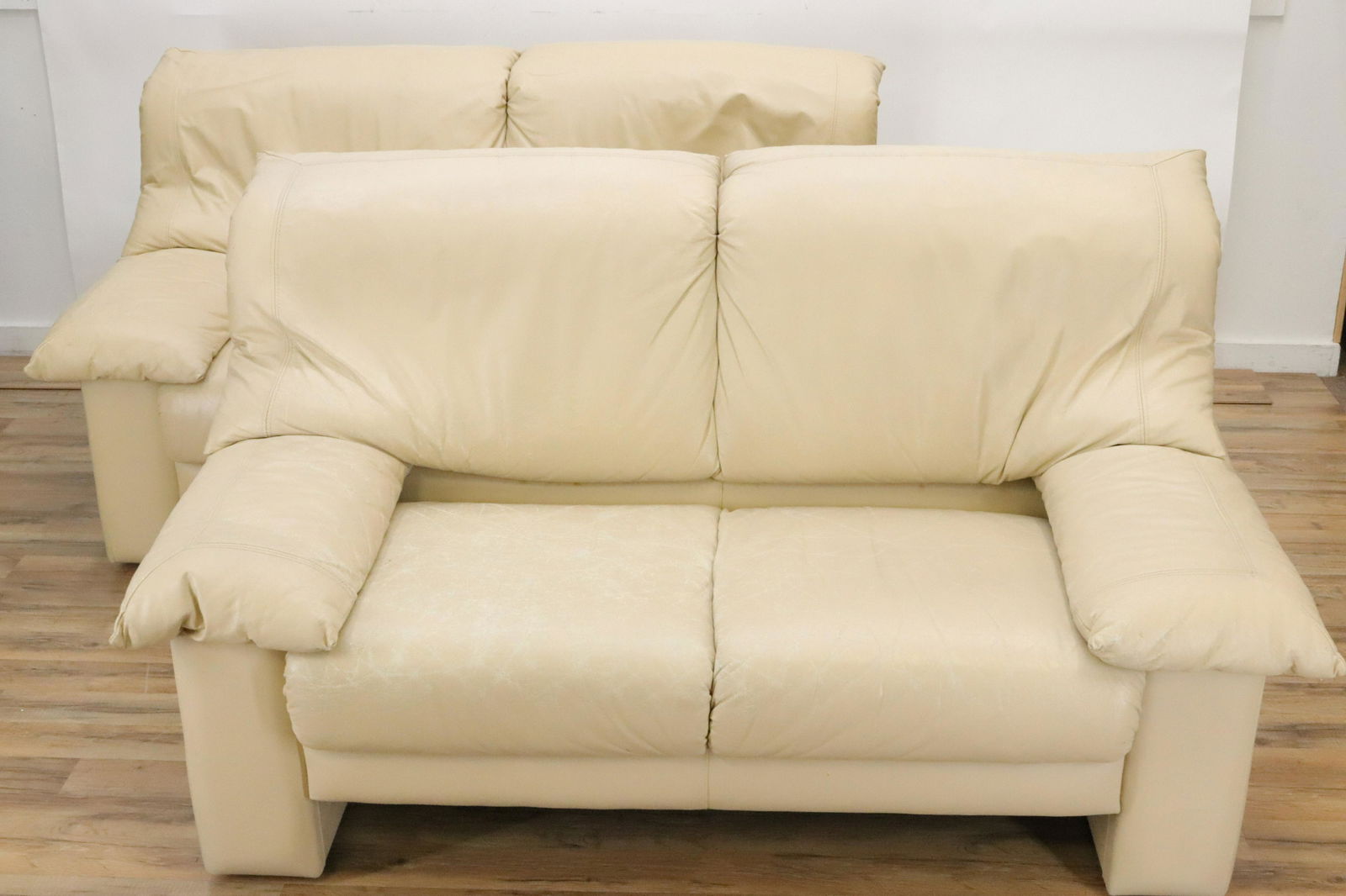 Pair 80's Cream Leather Upholstered Love Seats: Pair 1980's Cream Leather Upholstered Love Seats Dimensions: 35" H x 60" W x 36" D Property from a private Alpine, New Jersey collection (MLEN468/2)(MS)