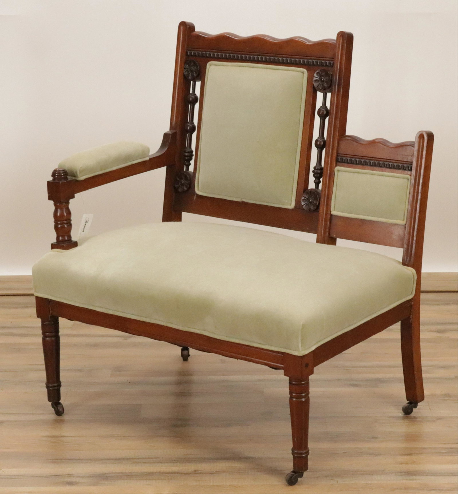 Vintage Childs or Parent-Child Single Arm Setee: Wood frame with grey-green upholstered seat, back, arm. Rod and ball with flowerhead/rosette spindles. Turned front legs, arm support. On casters. Dimensions: 35.5"H x 30W x 22D seat 16H (WIFO186)(JP)